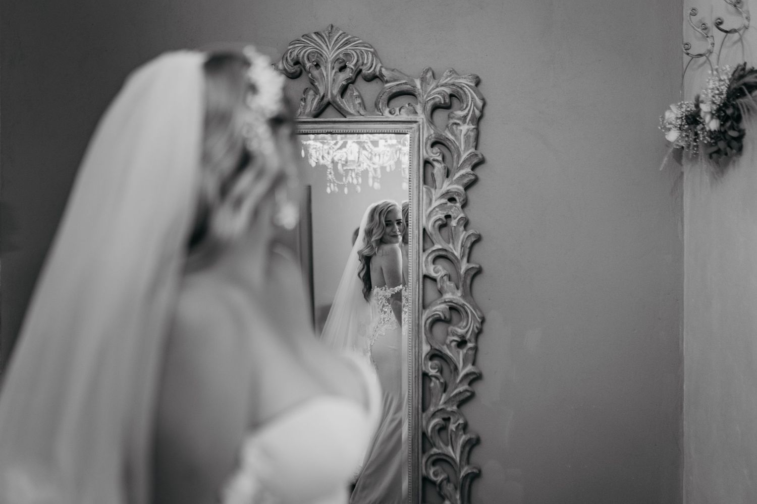 Artistic black and white reflection of bride in ornate vintage mirror.