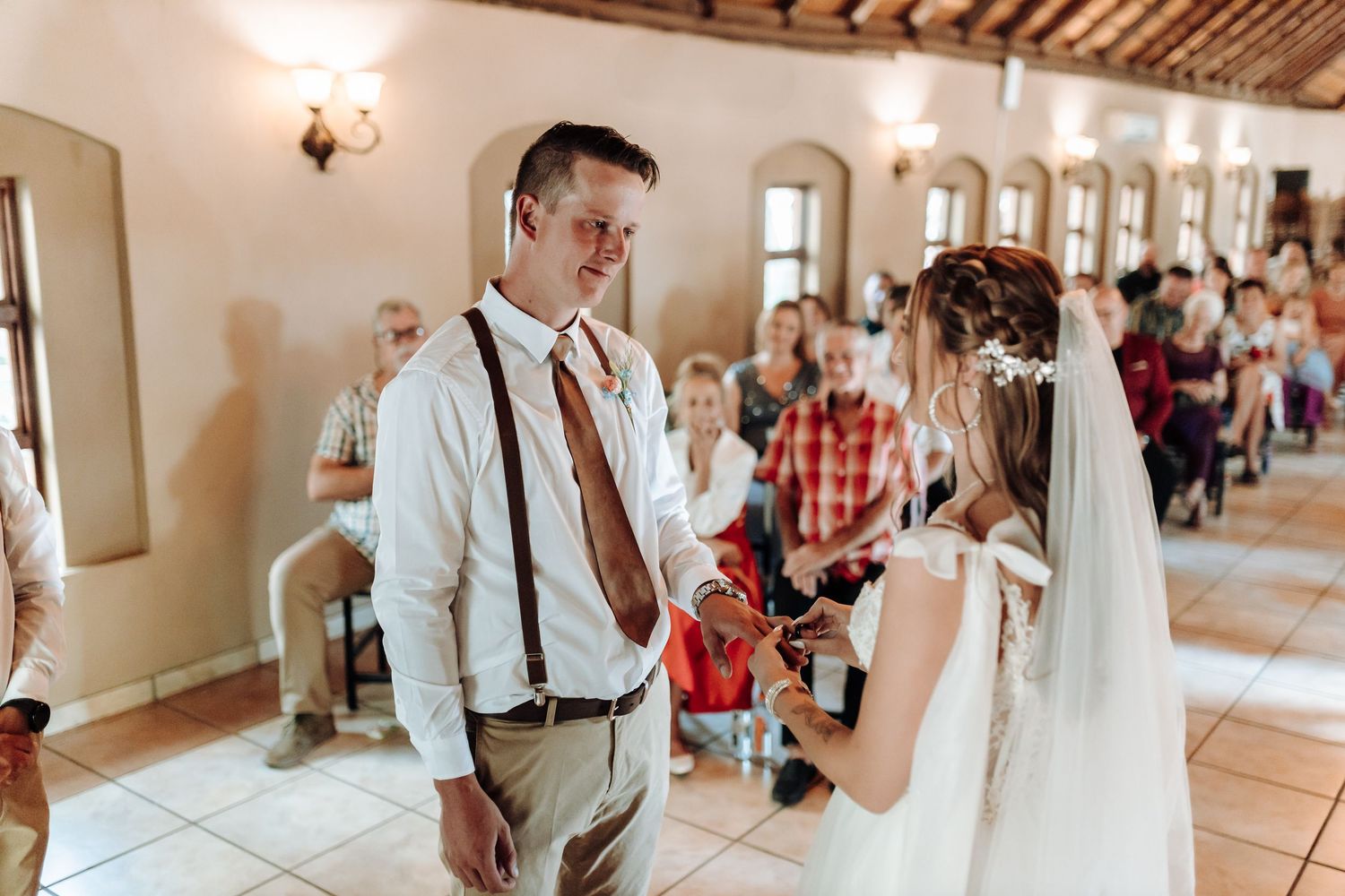 Couple shares emotional moment during wedding ceremony in rustic indoor venue.