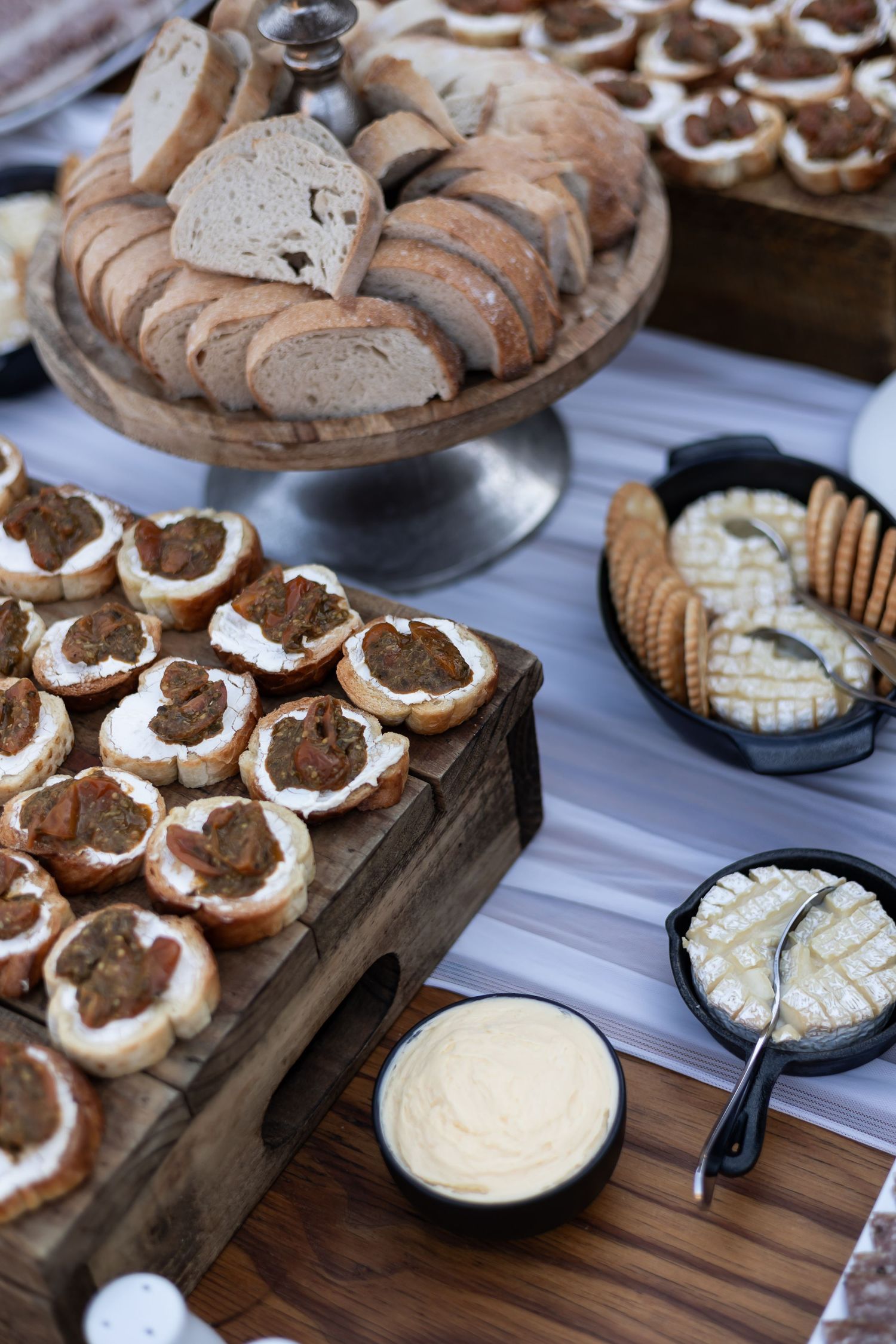 Artisanal bread and appetizers displayed on wooden boards with sliced bread rounds topped with spreads and dips.