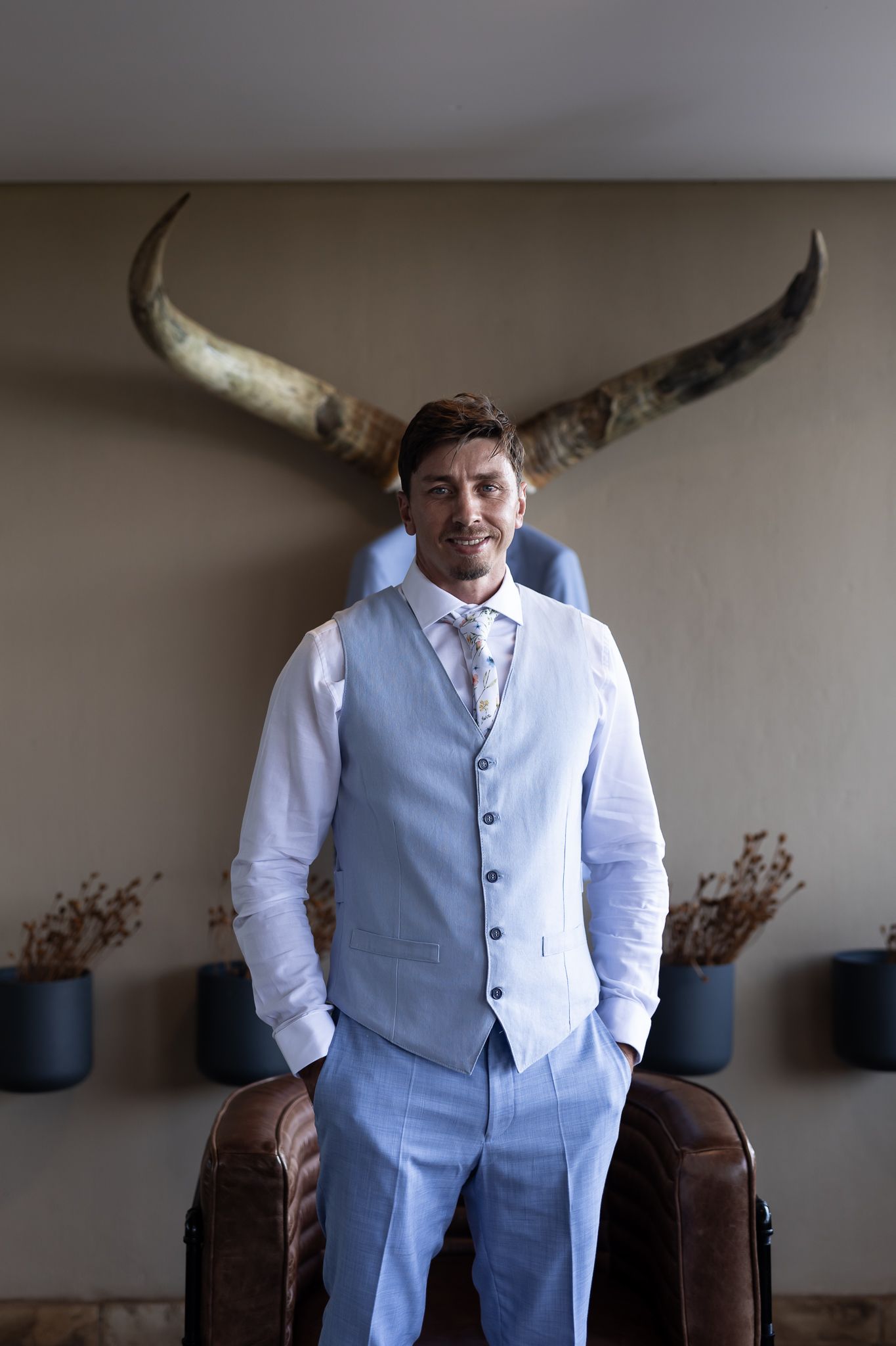 Elegant wedding attire with light blue vest against wall with mounted longhorns.
