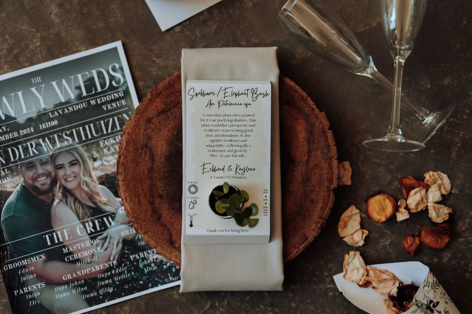 Wedding details including invitation, wood charger plate, and champagne glass on dark surface.