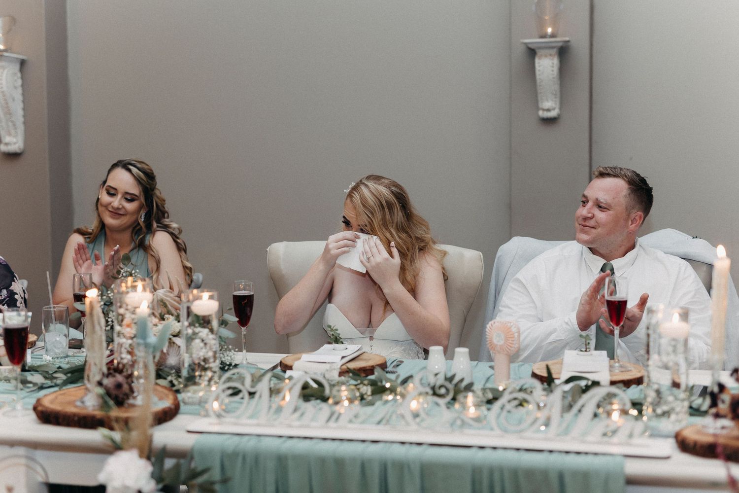 Guests seated at an elegant reception table with mint green decor and taper candles.