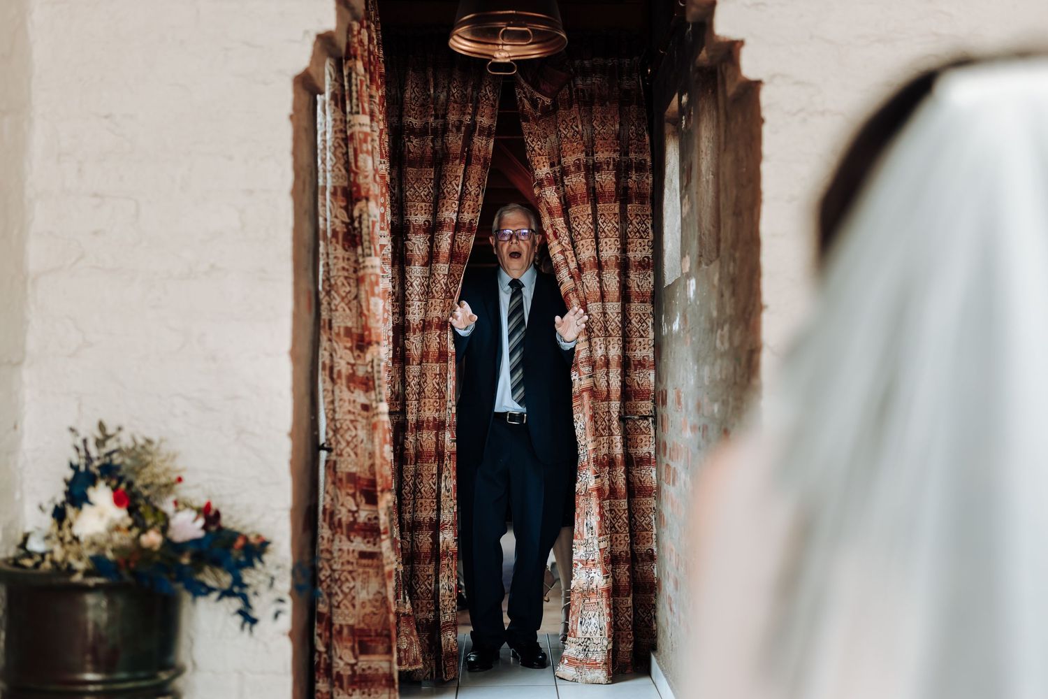 A person in formal attire standing in a rustic archway entrance.