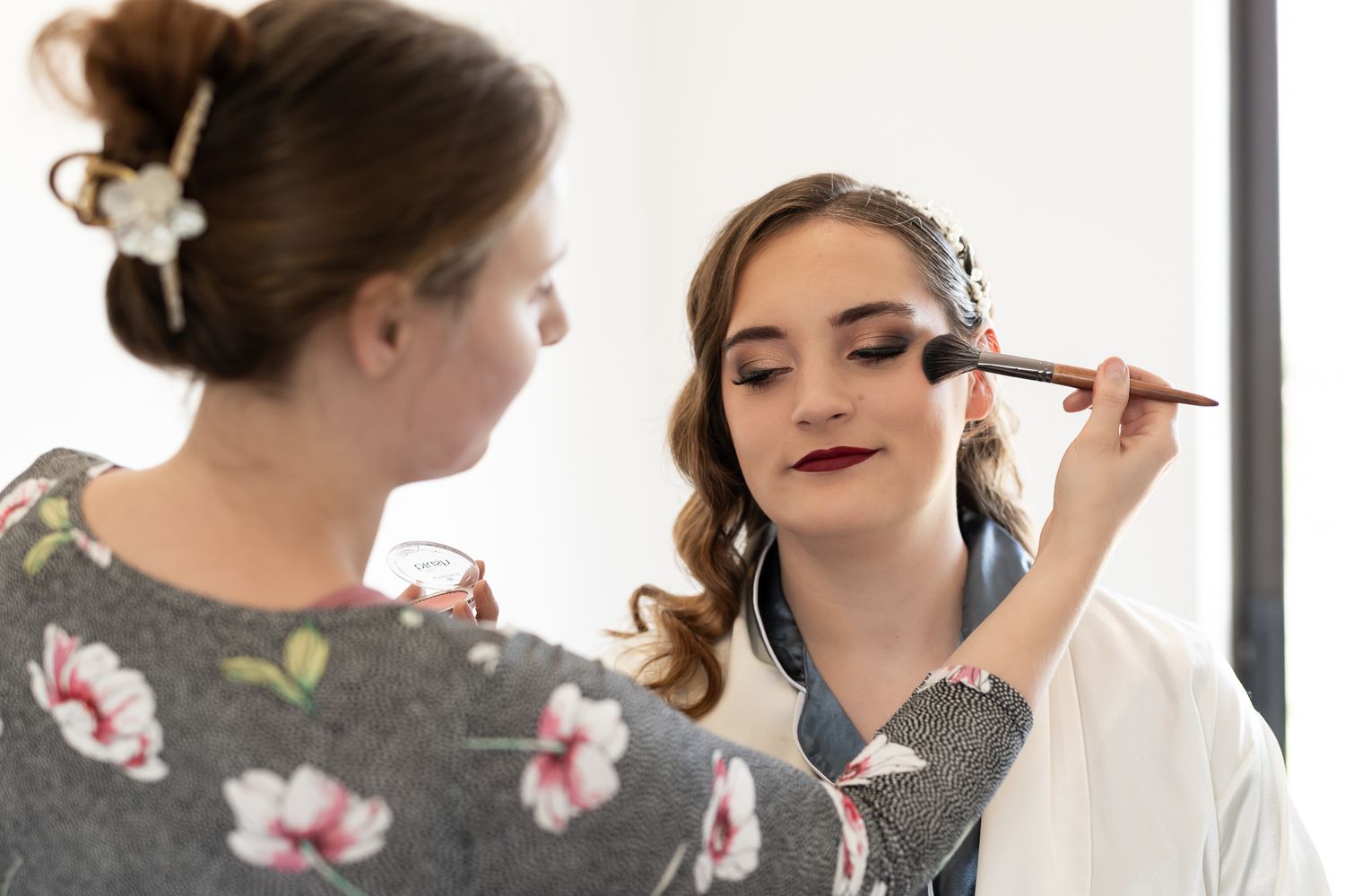 Makeup application in progress with brushes and cosmetics during wedding preparation.