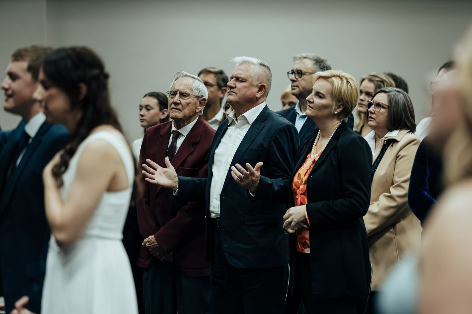 Wedding guests gather in formal attire watching an emotional ceremony moment in progress.