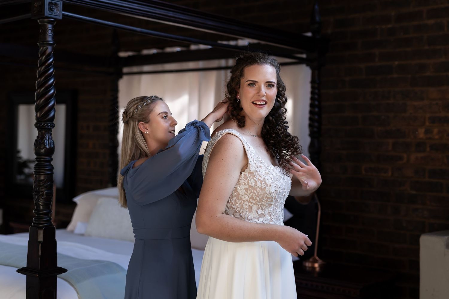 A group of wedding guests gather during an evening reception at a rustic brick-walled venue.