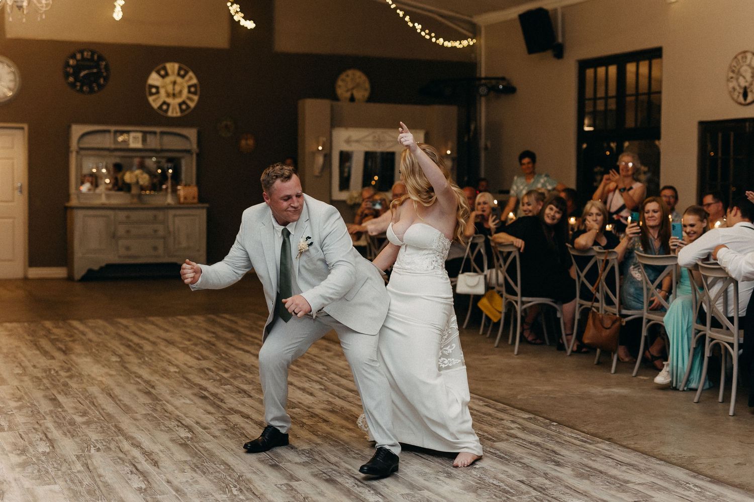 Joyful dance moves captured during wedding celebration with guests watching from their seats.