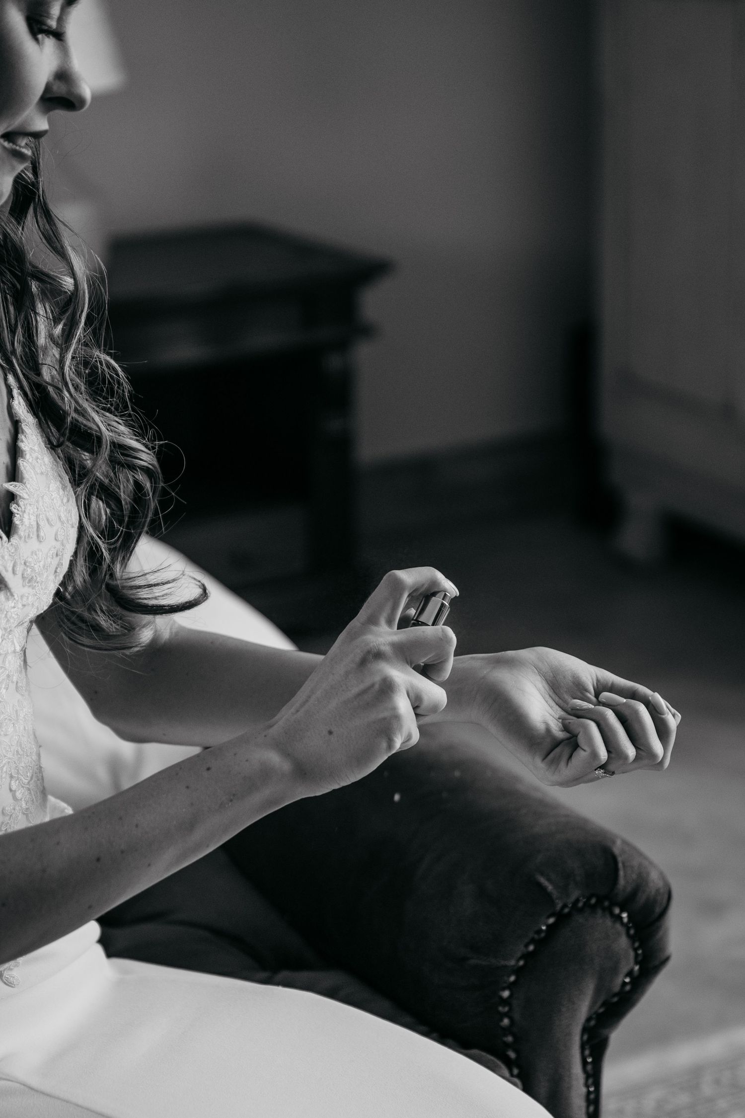 Black and white close-up of bride applying perfume to wrist.