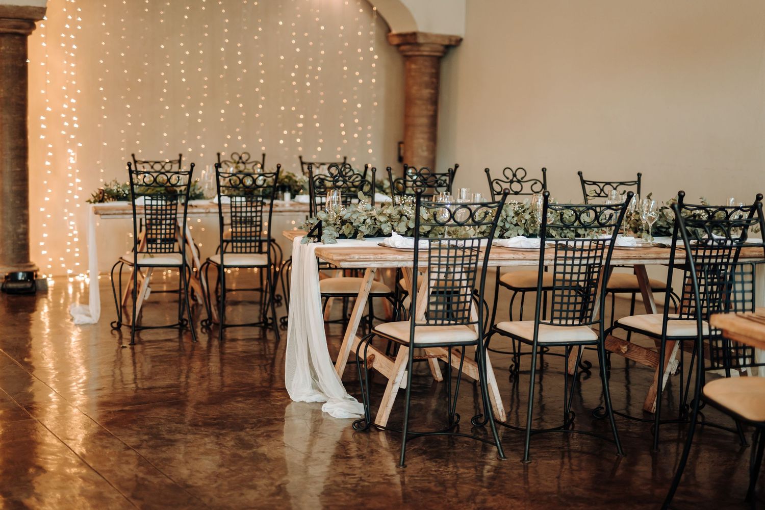 Elegant wedding reception setup with twinkle lights and black chiavari chairs.