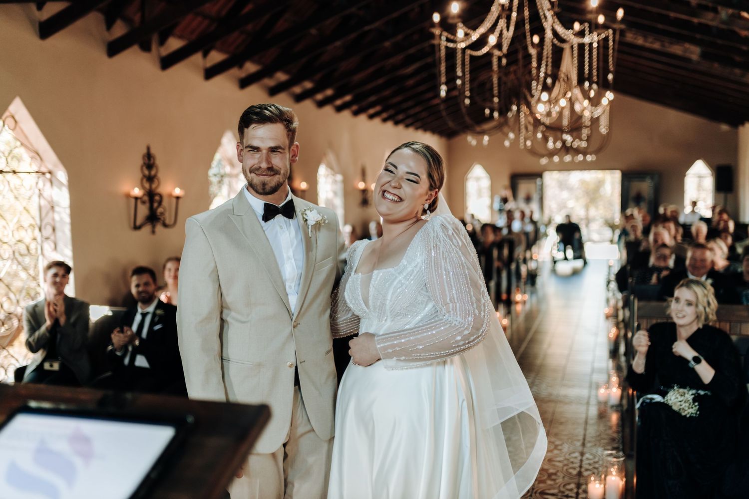Newlyweds share a light moment during their wedding ceremony in an elegant indoor venue.