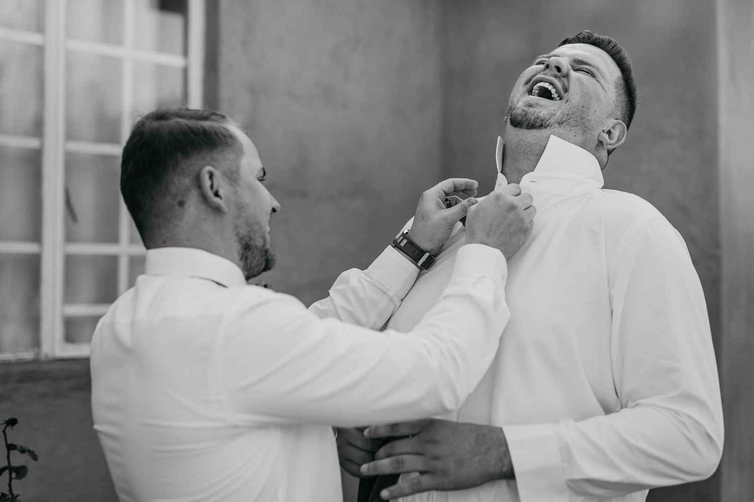 A sequence of black and white photos showing two men in white shirts sharing laughter and embracing in celebration.