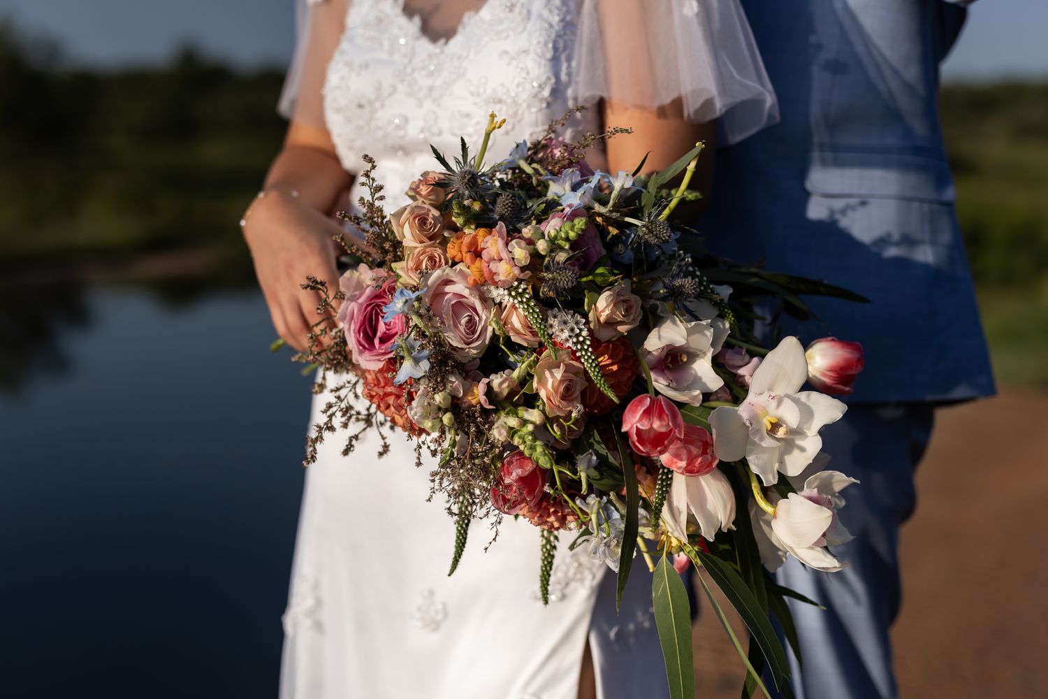 Rustic wedding bouquet with pink and white flowers against bridal dress.