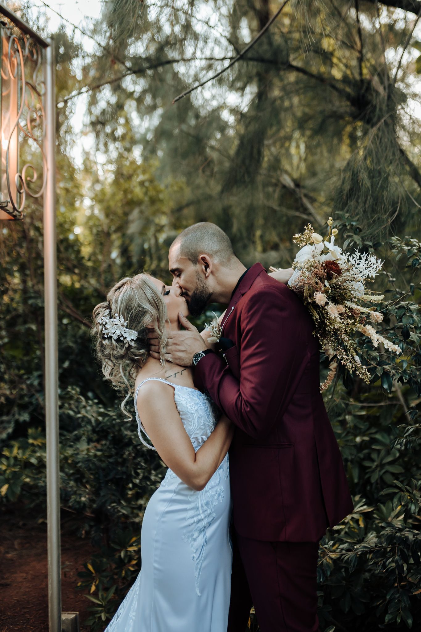 Romantic wedding portrait under a lantern with bride in blue gown and groom in burgundy suit.