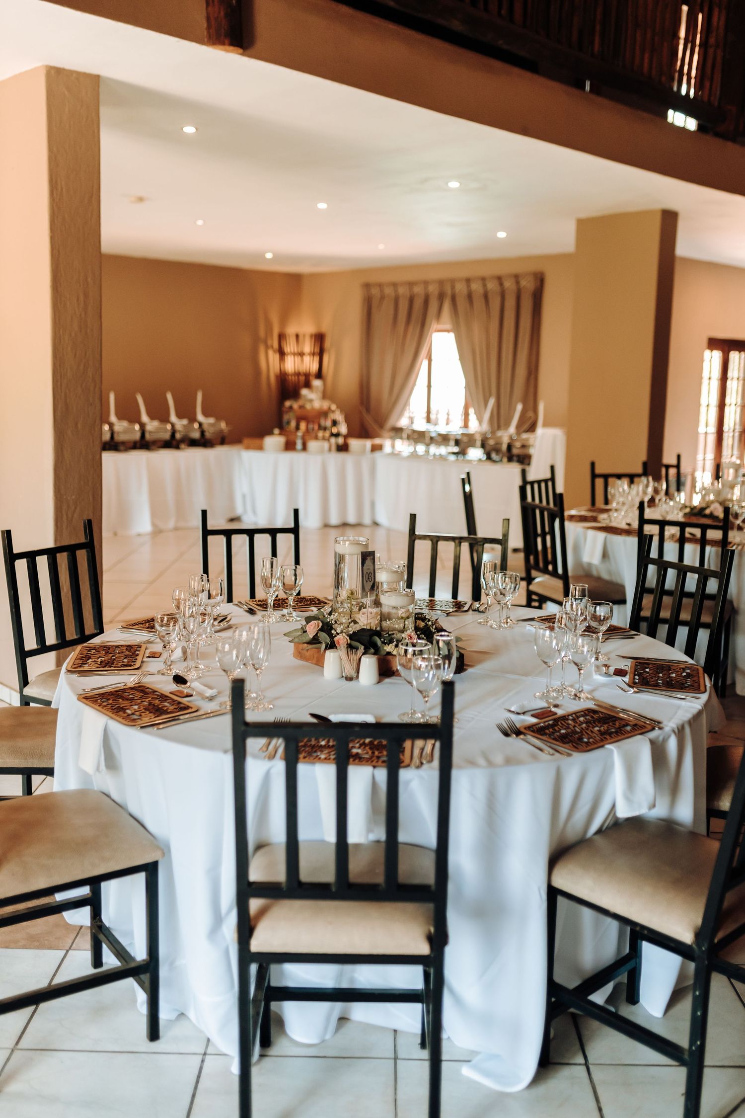 Wedding reception dining room with round tables, black chairs and white linens.