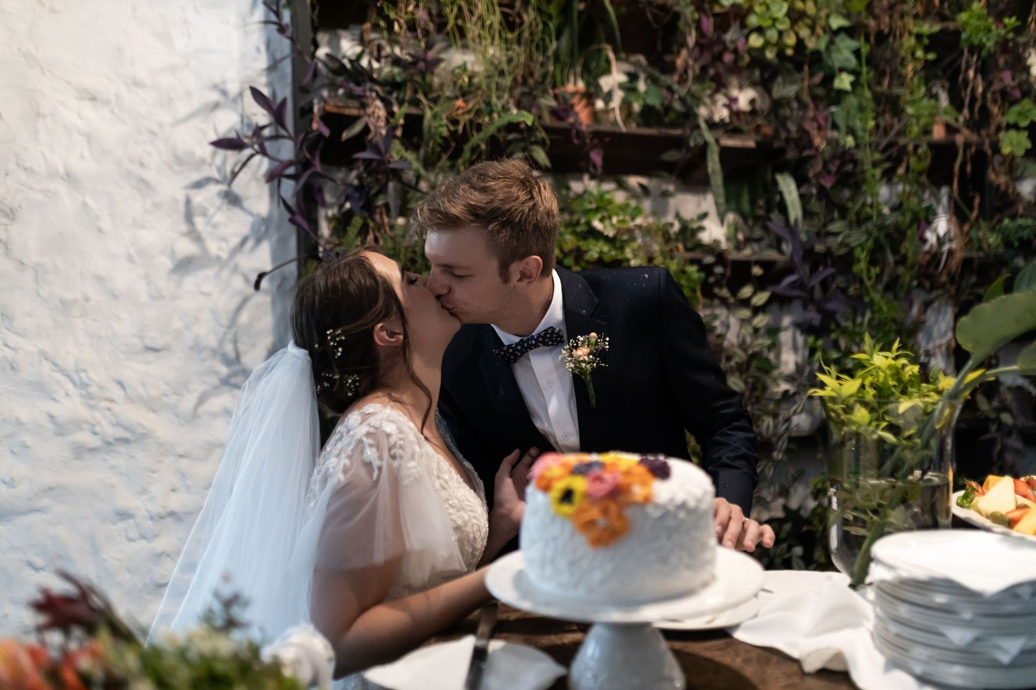 Romantic moment between newlyweds during cake cutting at garden wedding reception.