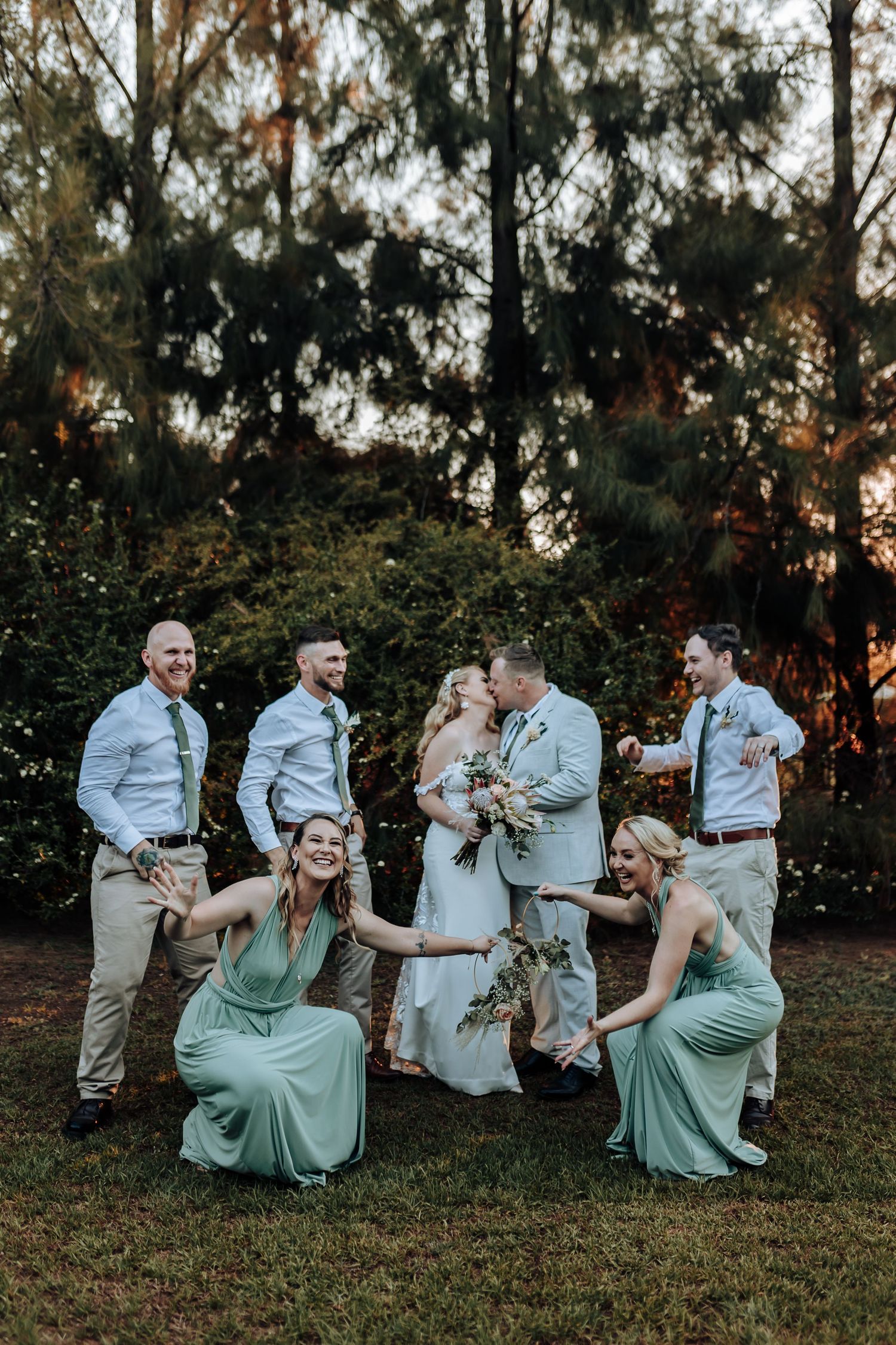 Fun wedding party photo with bridesmaids in mint dresses striking playful poses.