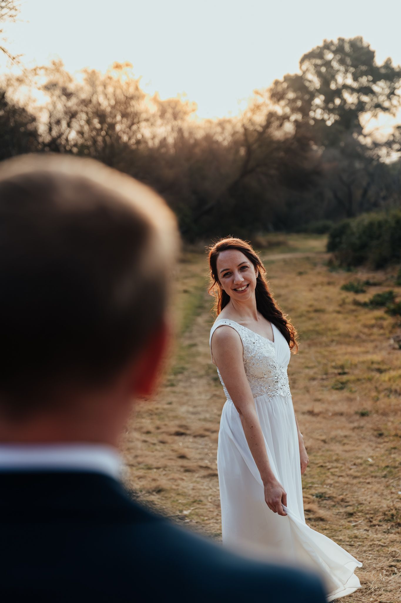 A beautiful outdoor wedding photo taken at sunset on a rustic dirt path.