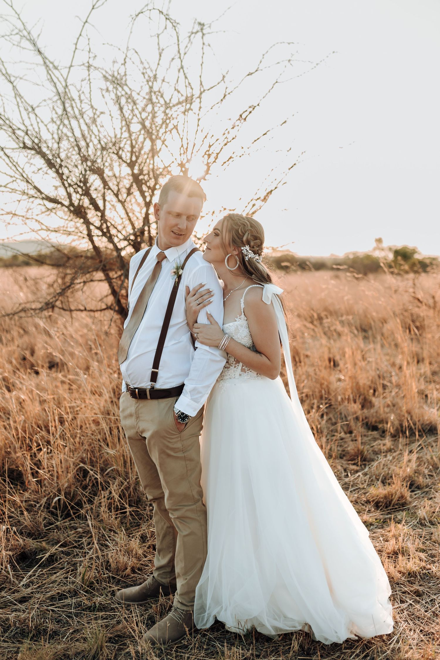 A romantic wedding photo captured in a rustic field during golden hour.