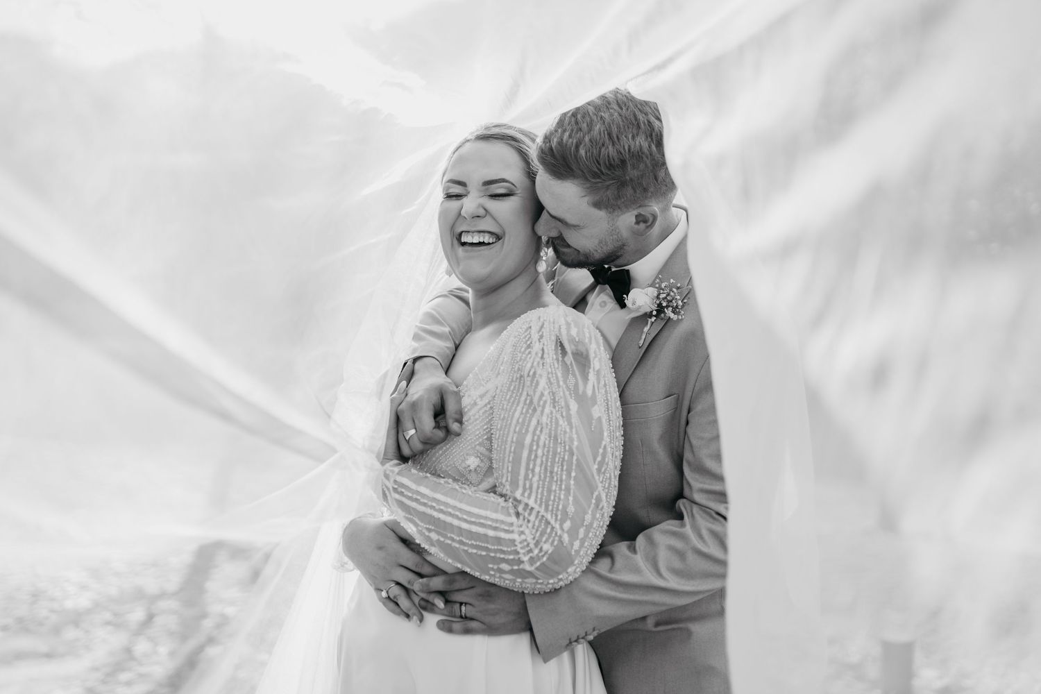 Black and white portrait of couple sharing intimate embrace during wedding photoshoot.