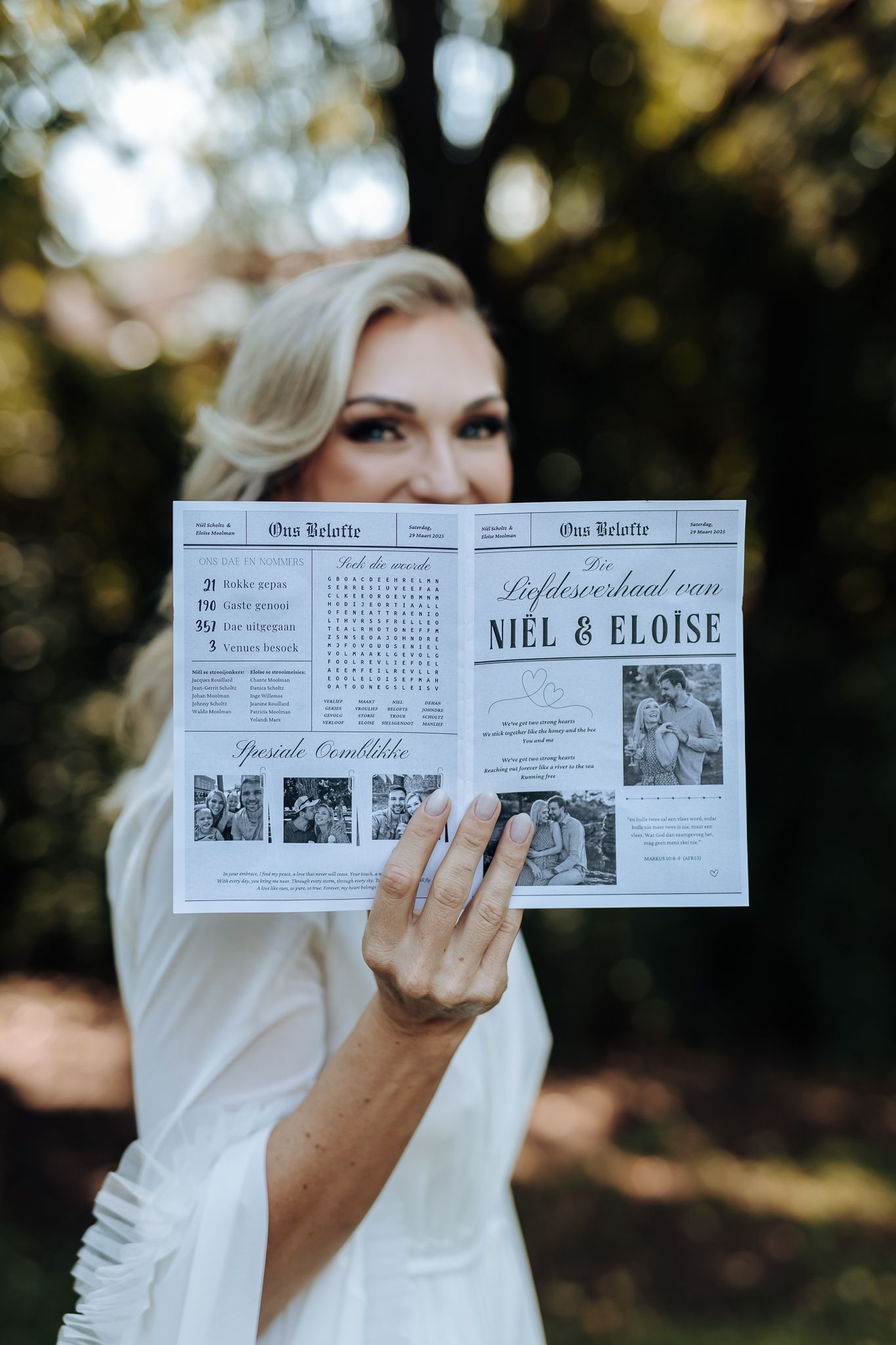 Custom wedding newspaper newsletter being displayed outdoors in natural lighting.