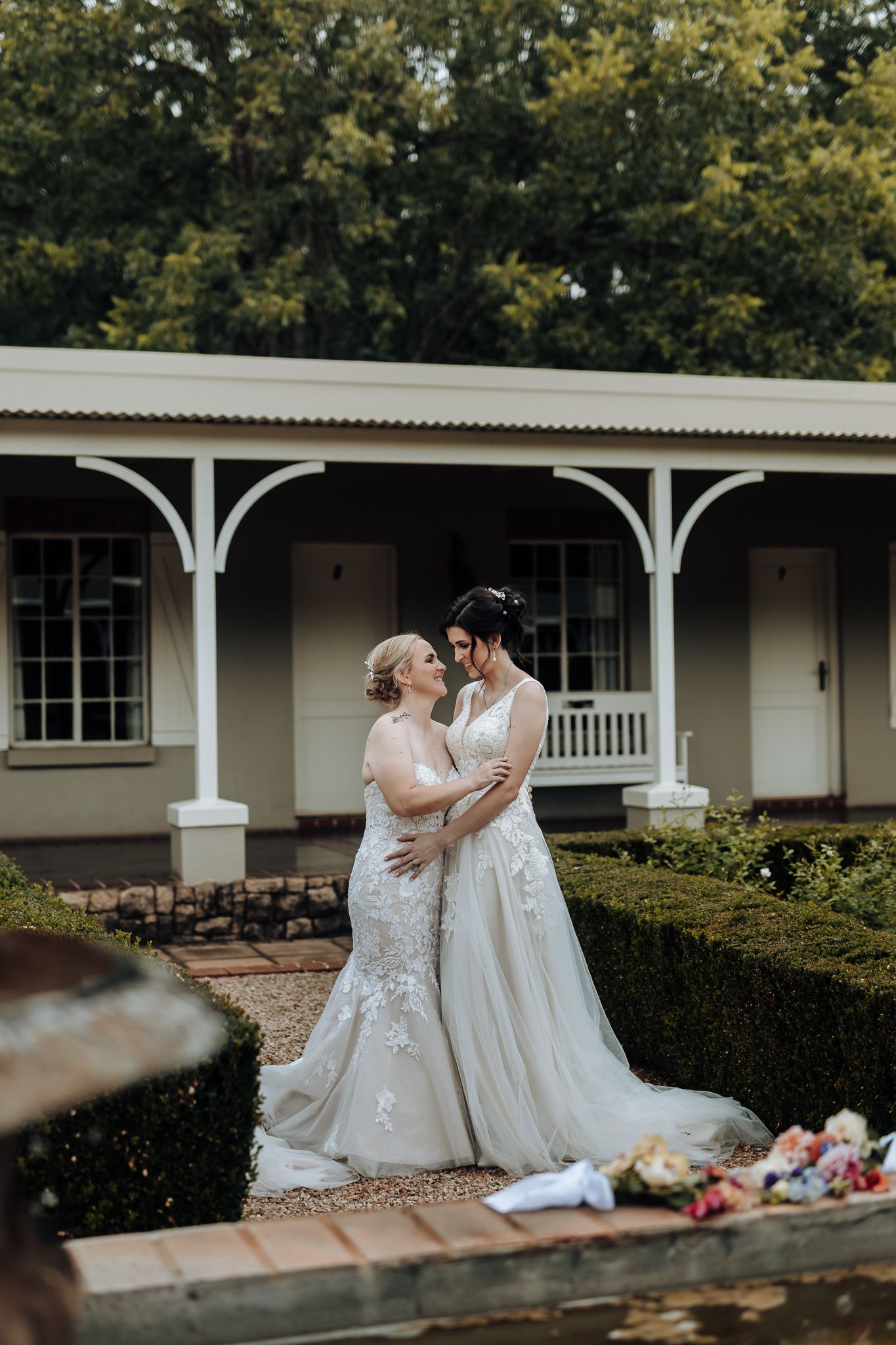 Wedding couple shares intimate moment on porch of colonial style venue with white columns.