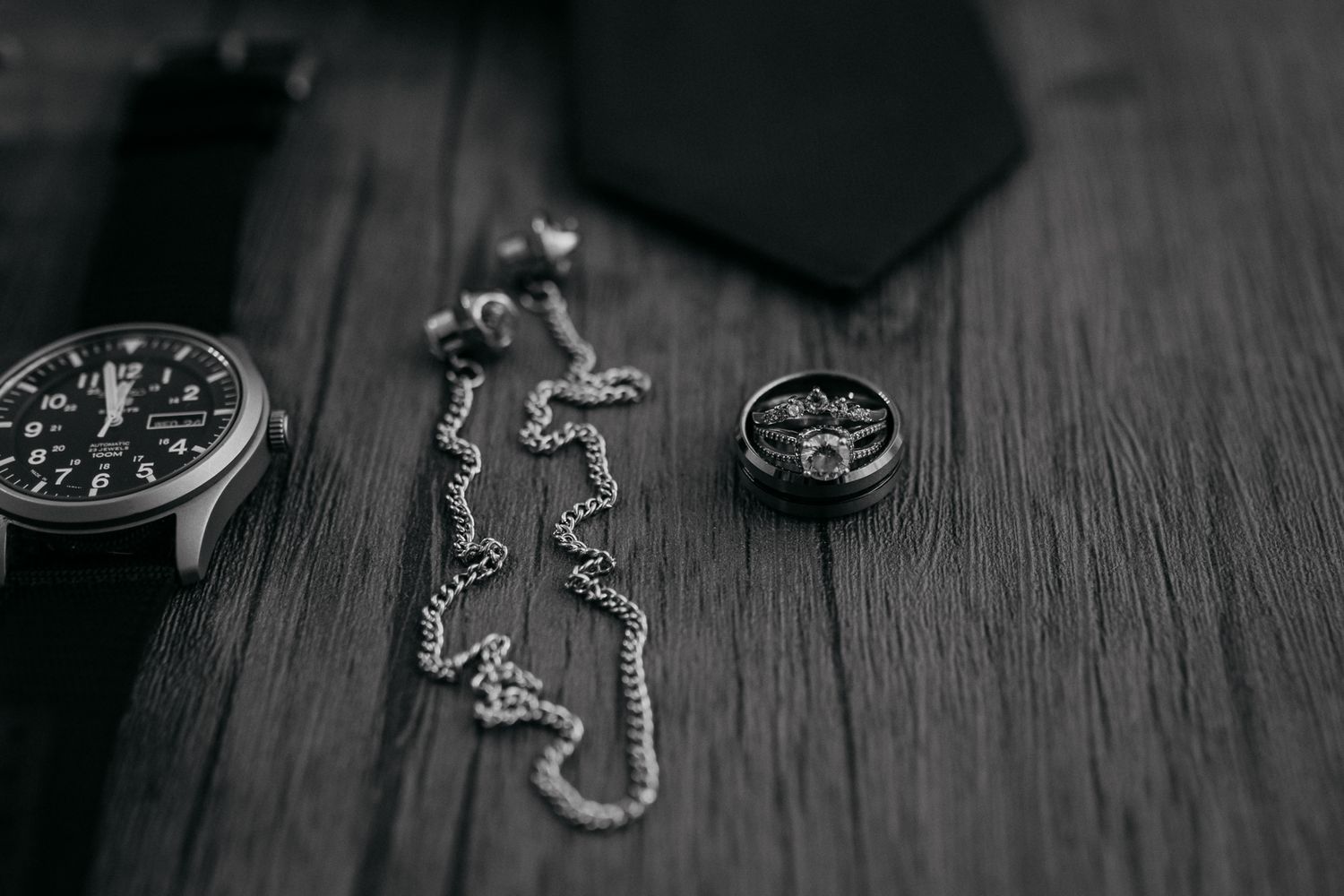 Vintage watch and silver chain displayed on dark wooden surface.