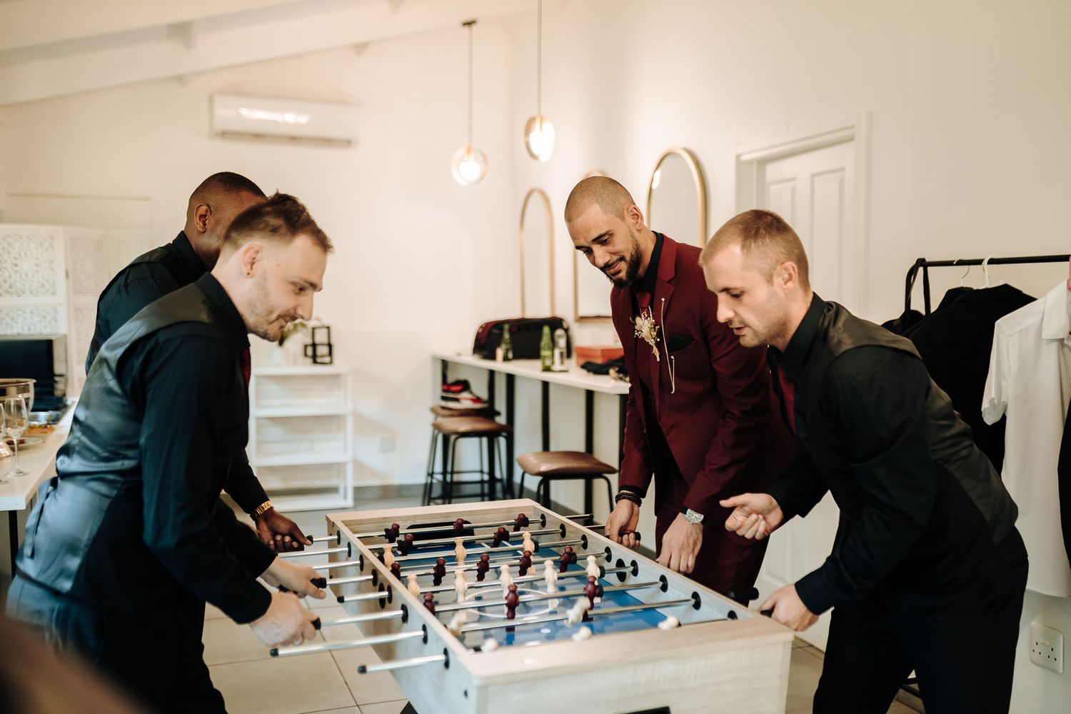 Friends gathered around a foosball table enjoying a competitive game indoors.