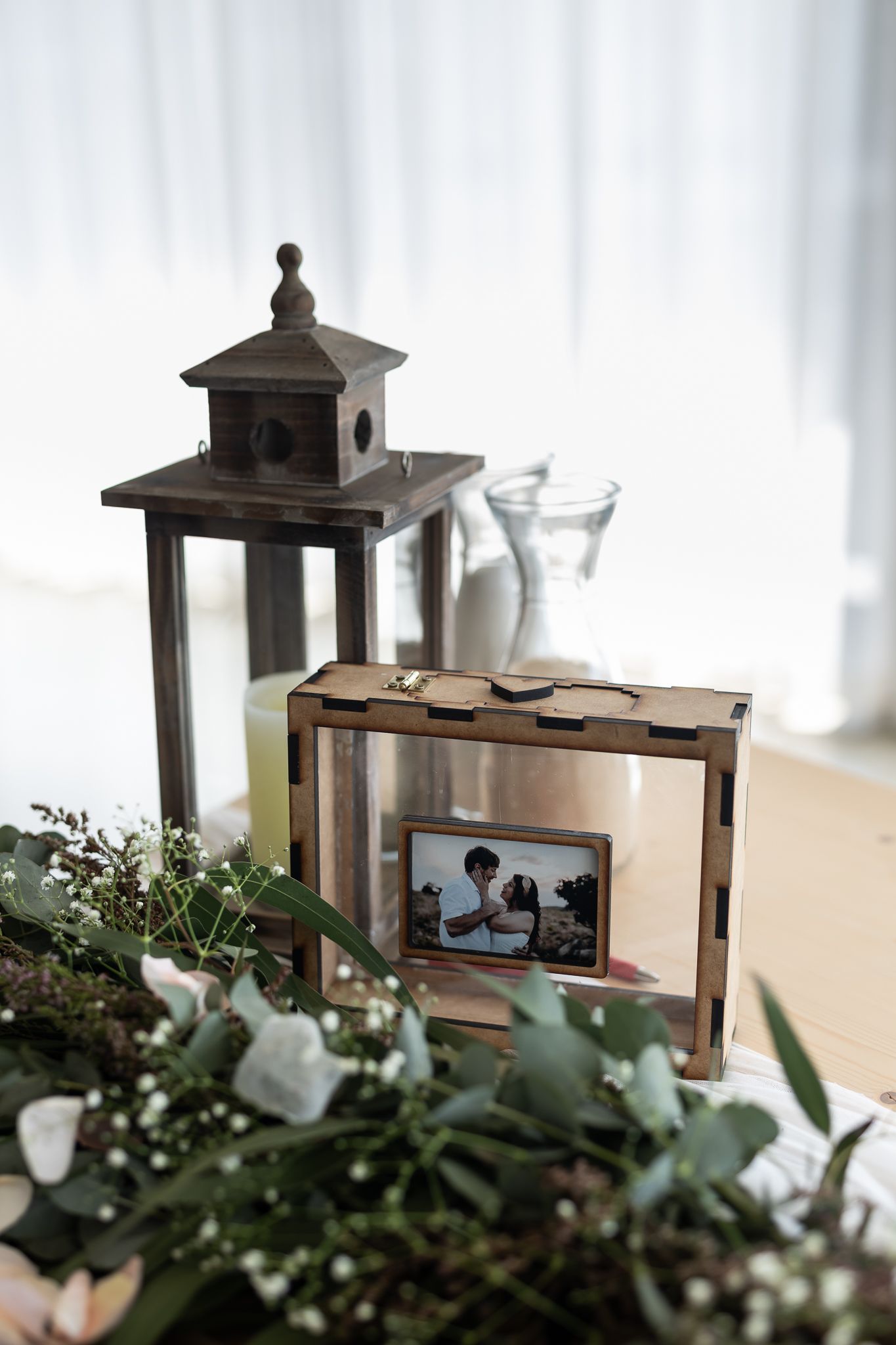 Decorative lantern and wooden frame display with eucalyptus greenery accents.