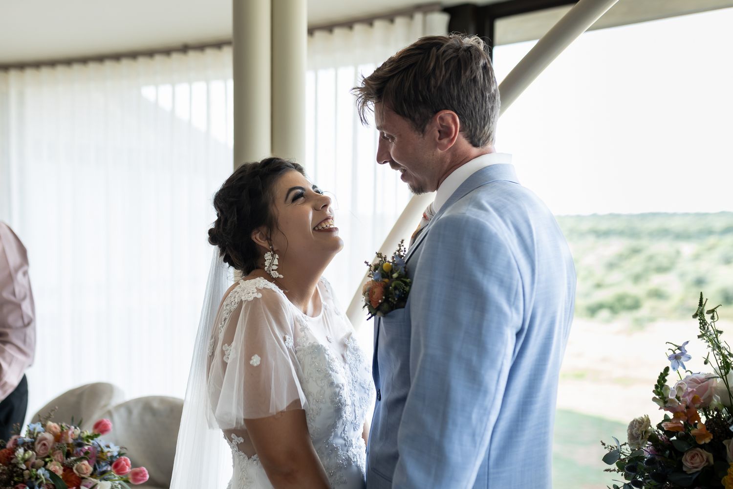 A couple shares an intimate moment during their wedding ceremony with natural light streaming in.