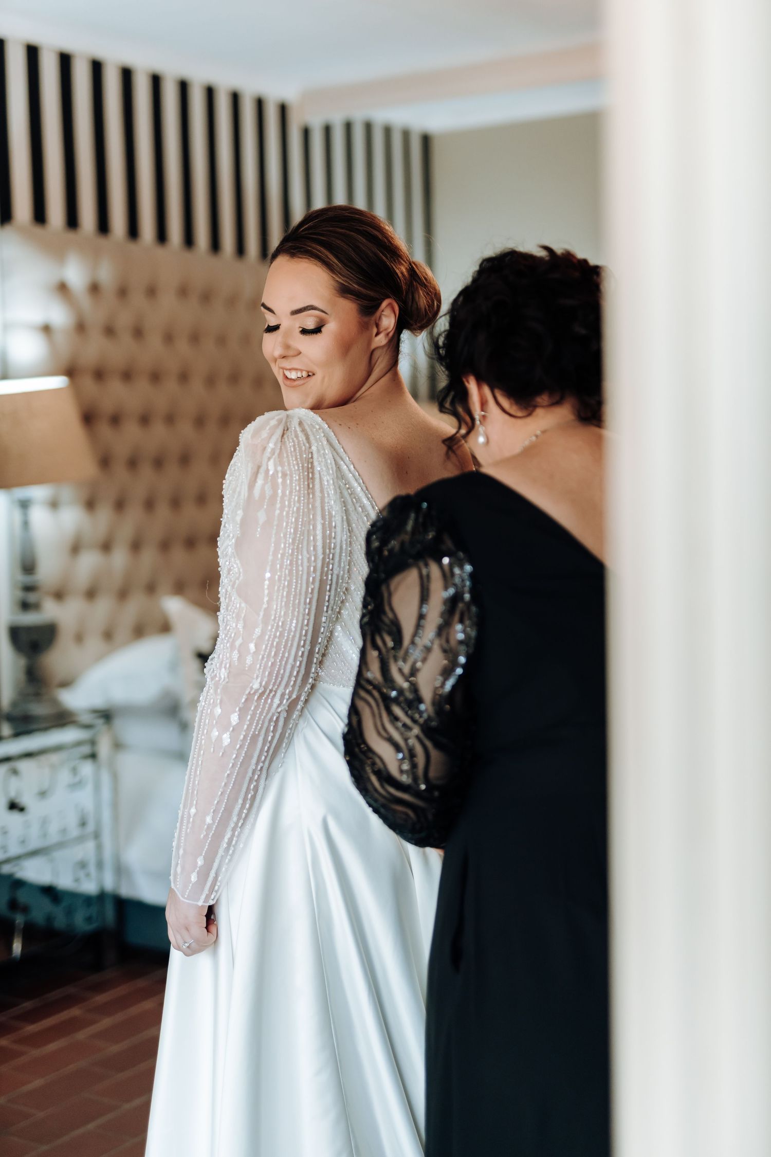 Final adjustments being made to a stunning long-sleeved white wedding dress.