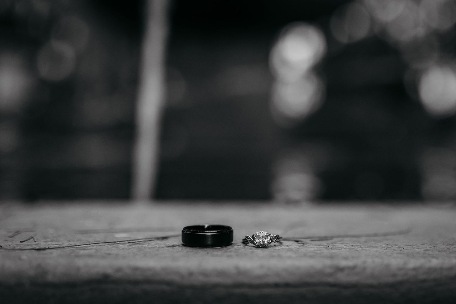 Black and white detail shot of wedding rings on a textured surface.