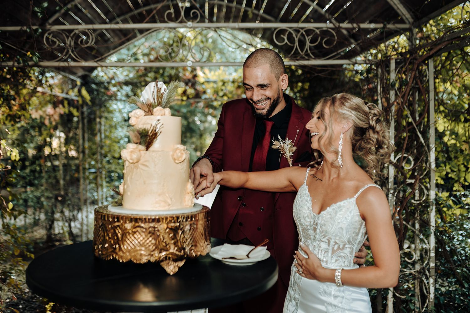 Couple cuts their elegant wedding cake in a glass-enclosed garden venue.