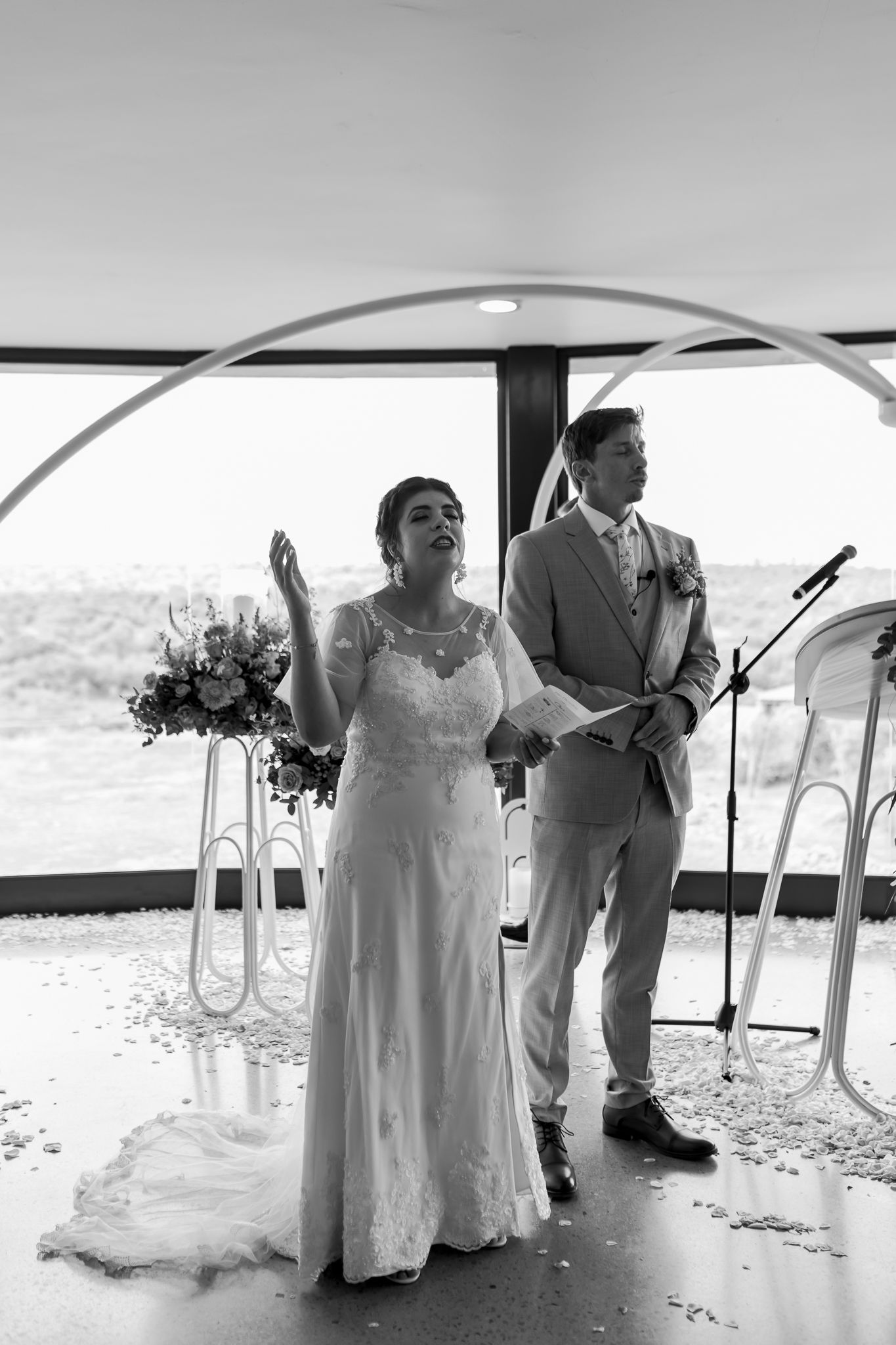 A couple shares an emotional moment under an arch during their black and white wedding ceremony.