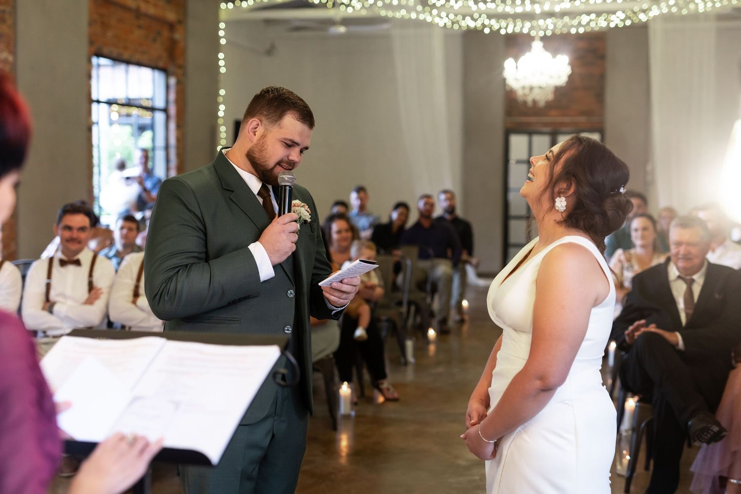 Wedding ceremony with exchange of vows in elegant venue with string lights.