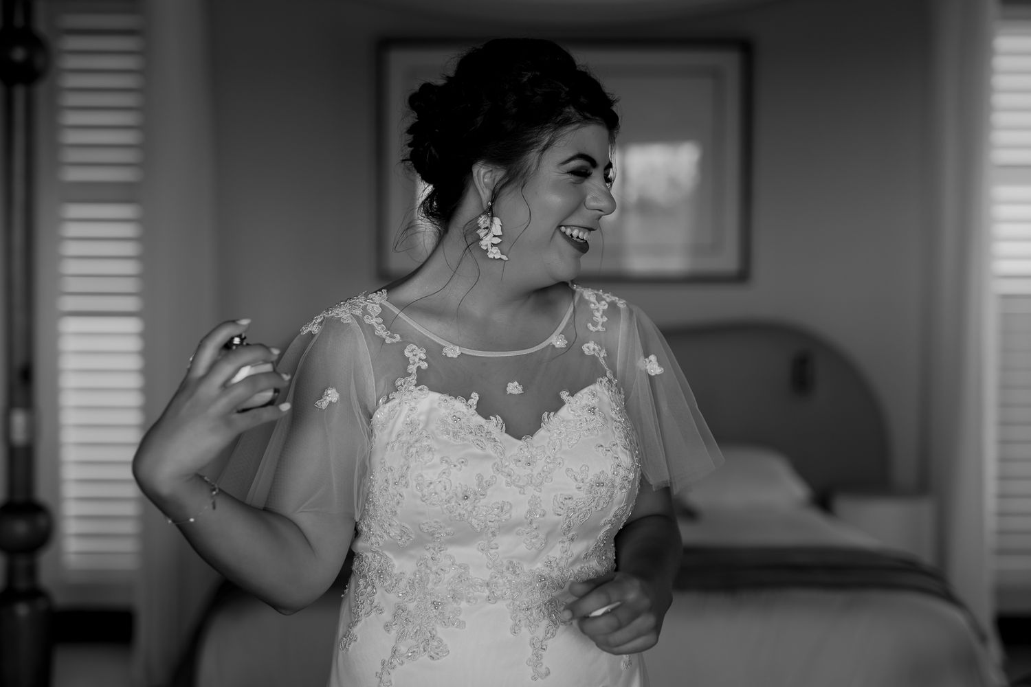 A black and white portrait of someone in a wedding dress with sheer sleeves.