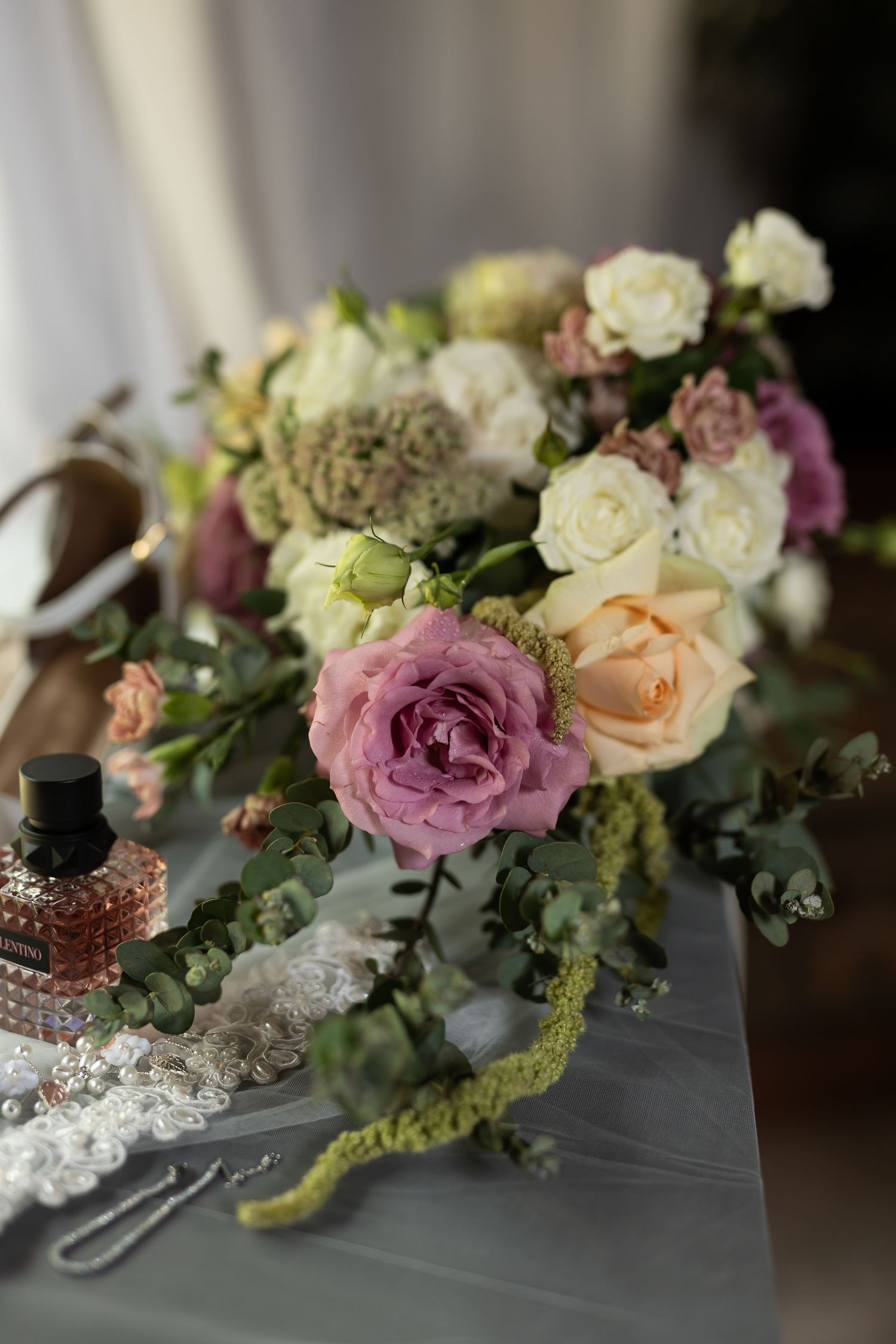 Close-up of romantic wedding bouquet with pink and cream roses on grey surface.