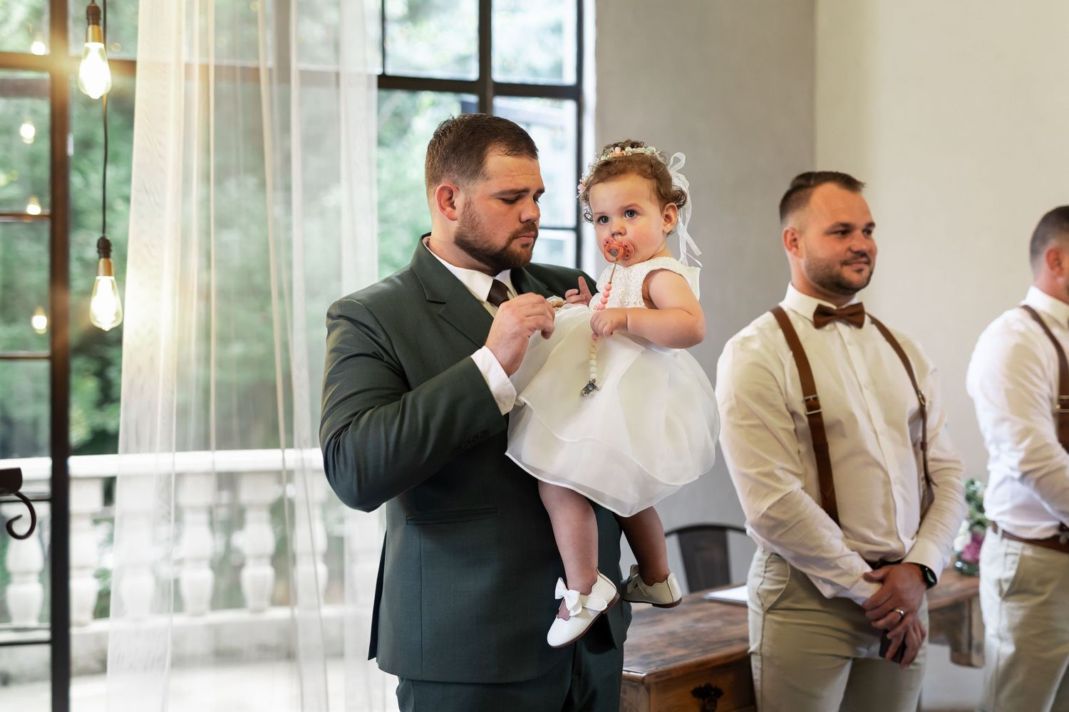 Sweet moment during wedding ceremony with formal attire and bright interior setting.