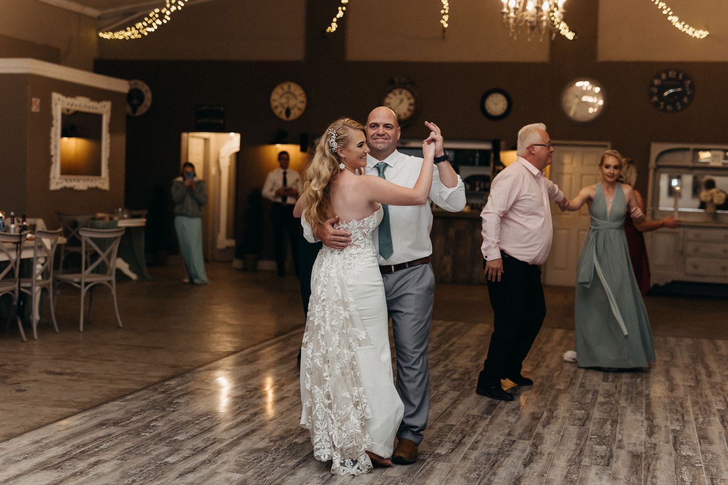 Wedding celebration dance with elegant decor and string lights illuminating wooden floor.