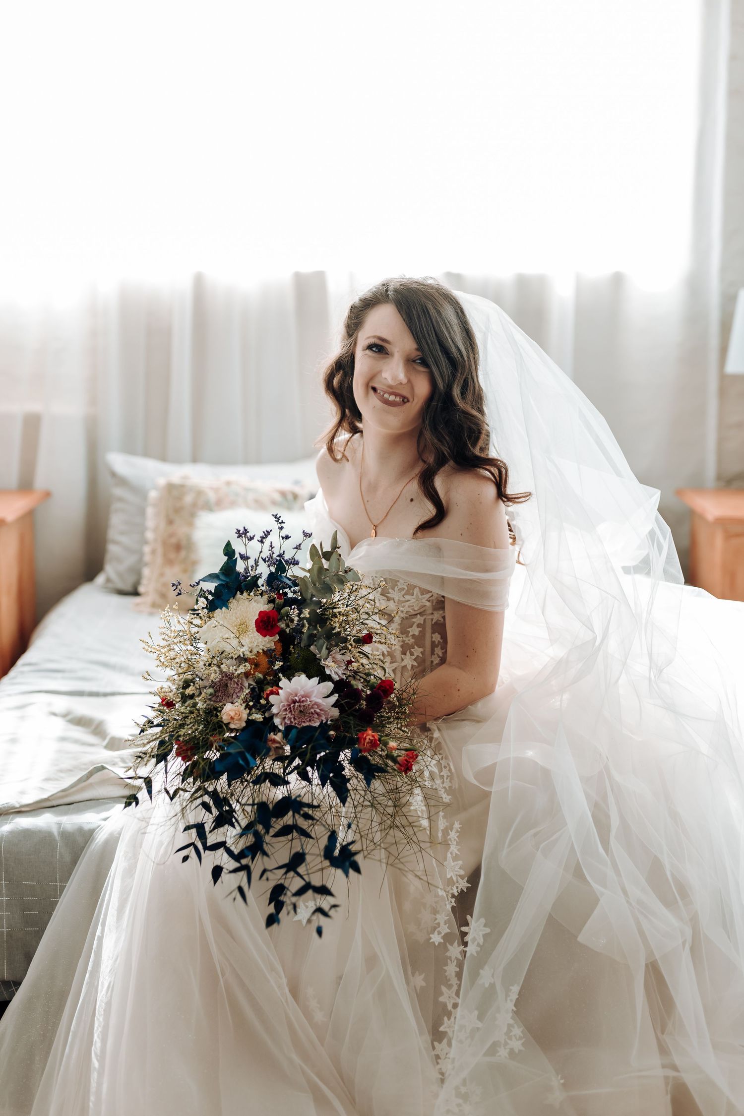 Stunning bridal portrait with cathedral veil and lush mixed flower bouquet in natural light.