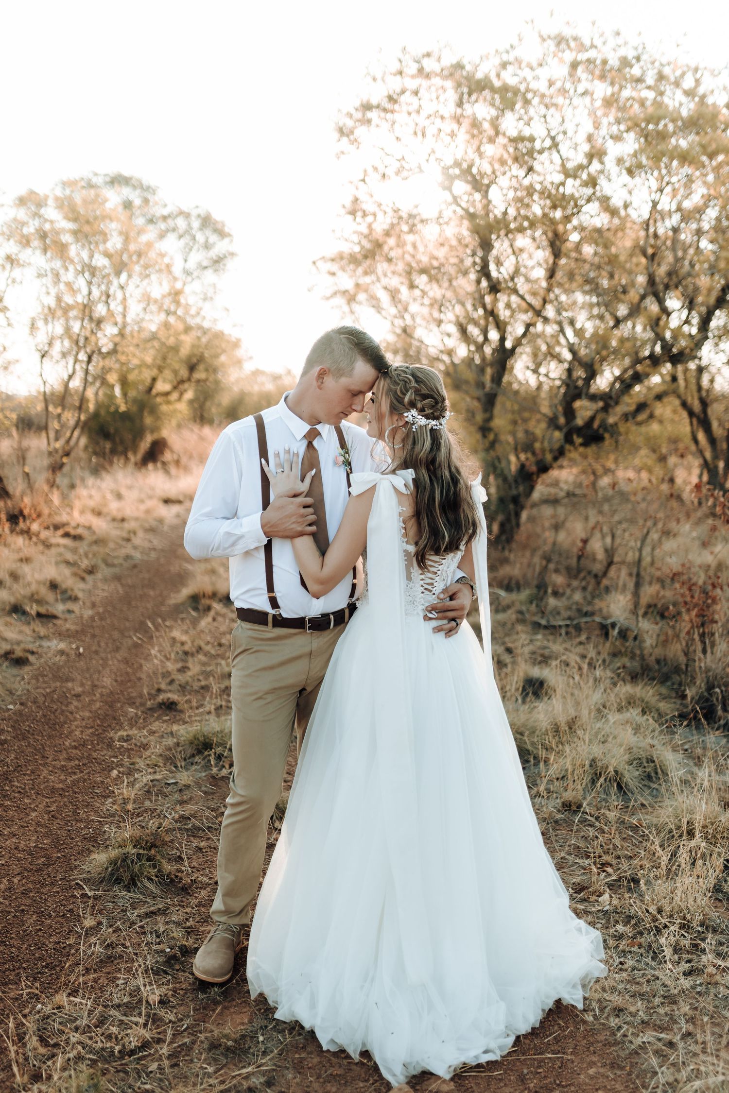 Wedding couple shares an intimate moment on a rustic trail at sunset.