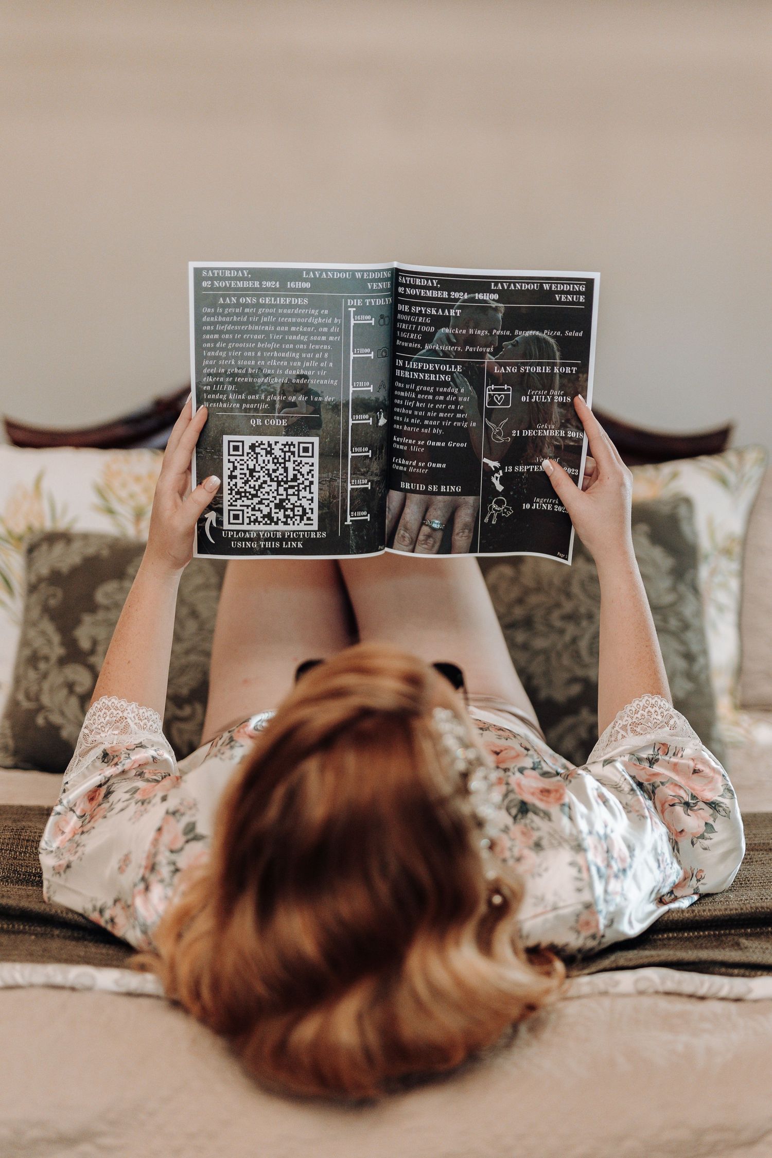 Overhead view of person lying on bed reading menu or brochure.