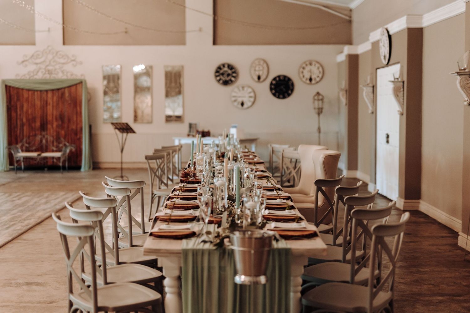 Elegant wedding reception venue with long table setup and cross-back chairs.