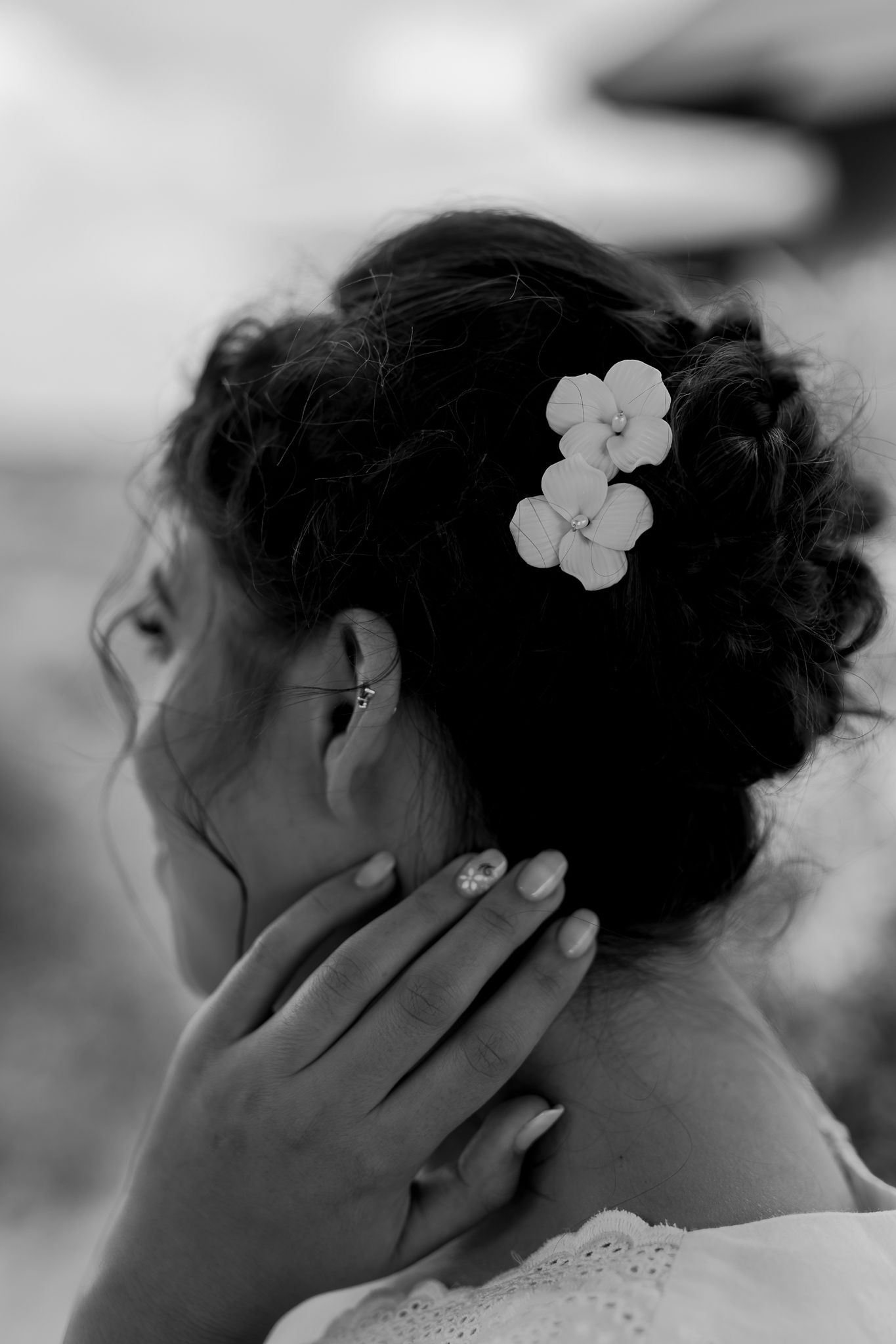 Black and white close-up of elegant updo hairstyle with white flower accessories.