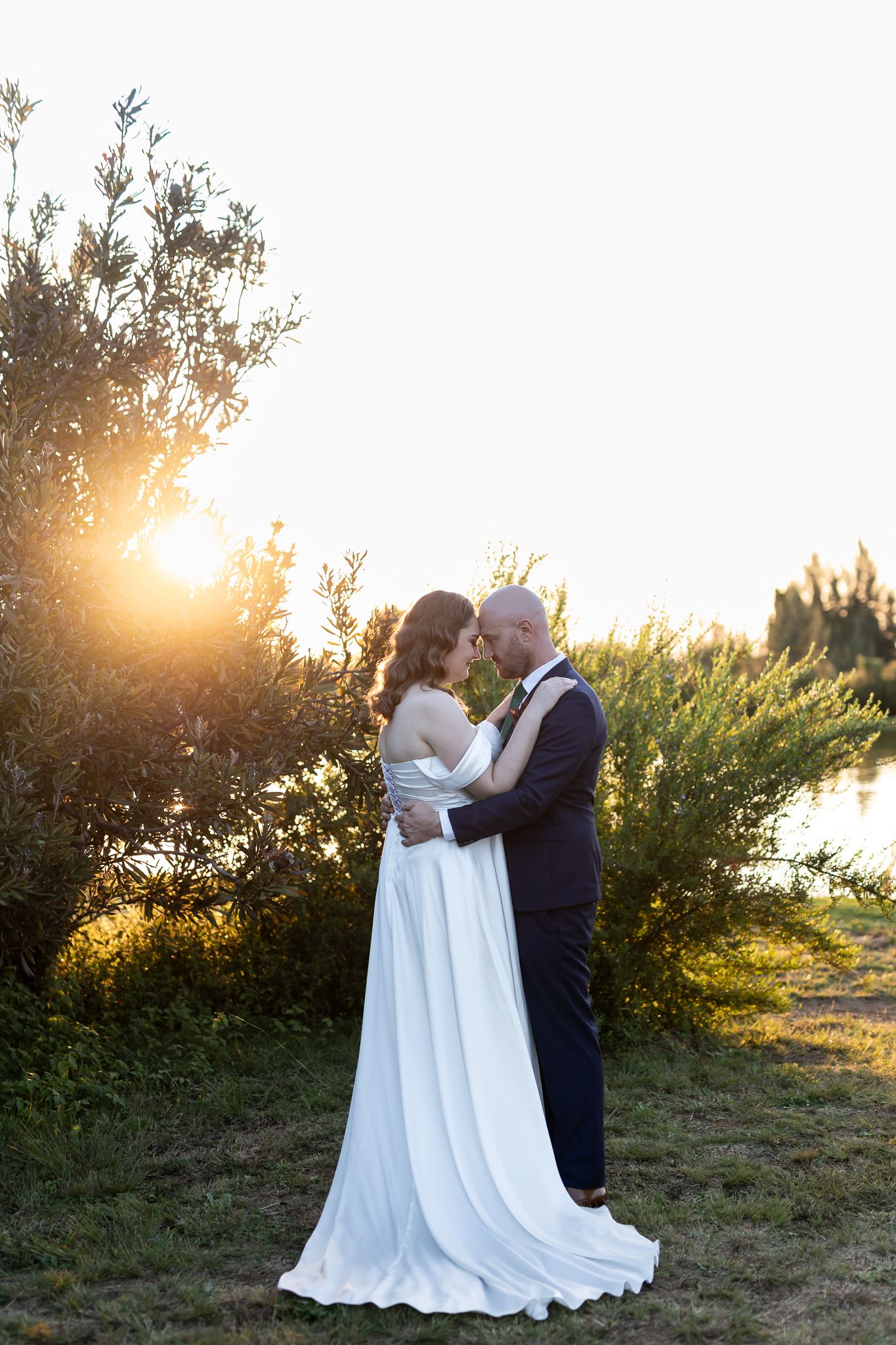A couple shares an intimate moment at sunset in a natural outdoor setting.