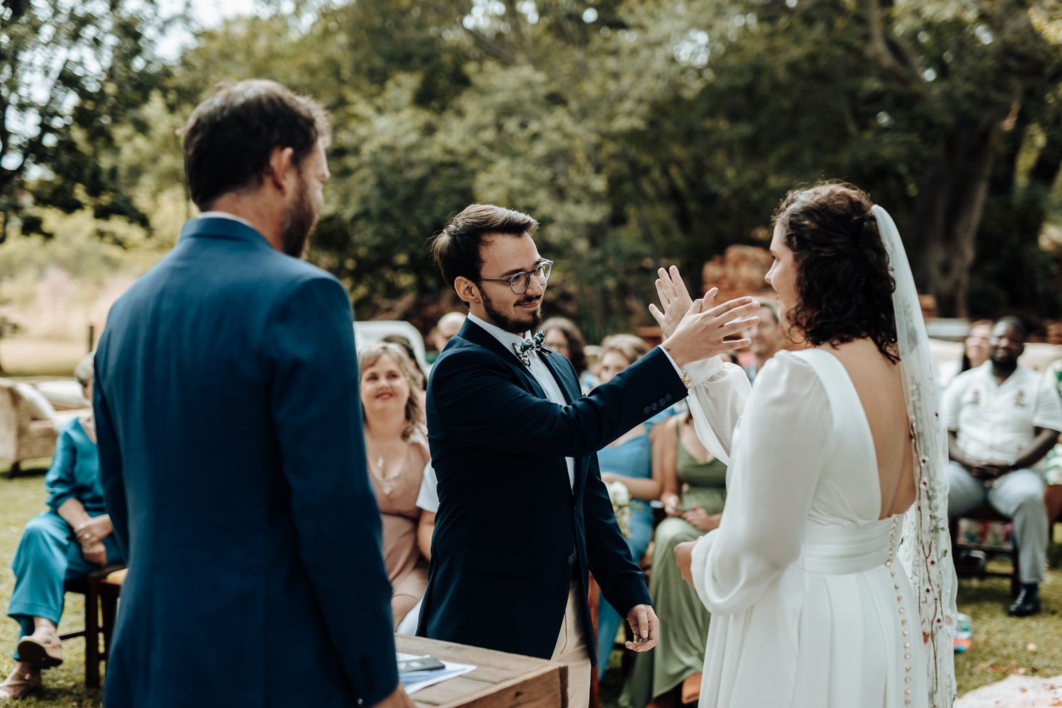 A joyful celebration moment during an outdoor wedding ceremony with guests looking on.
