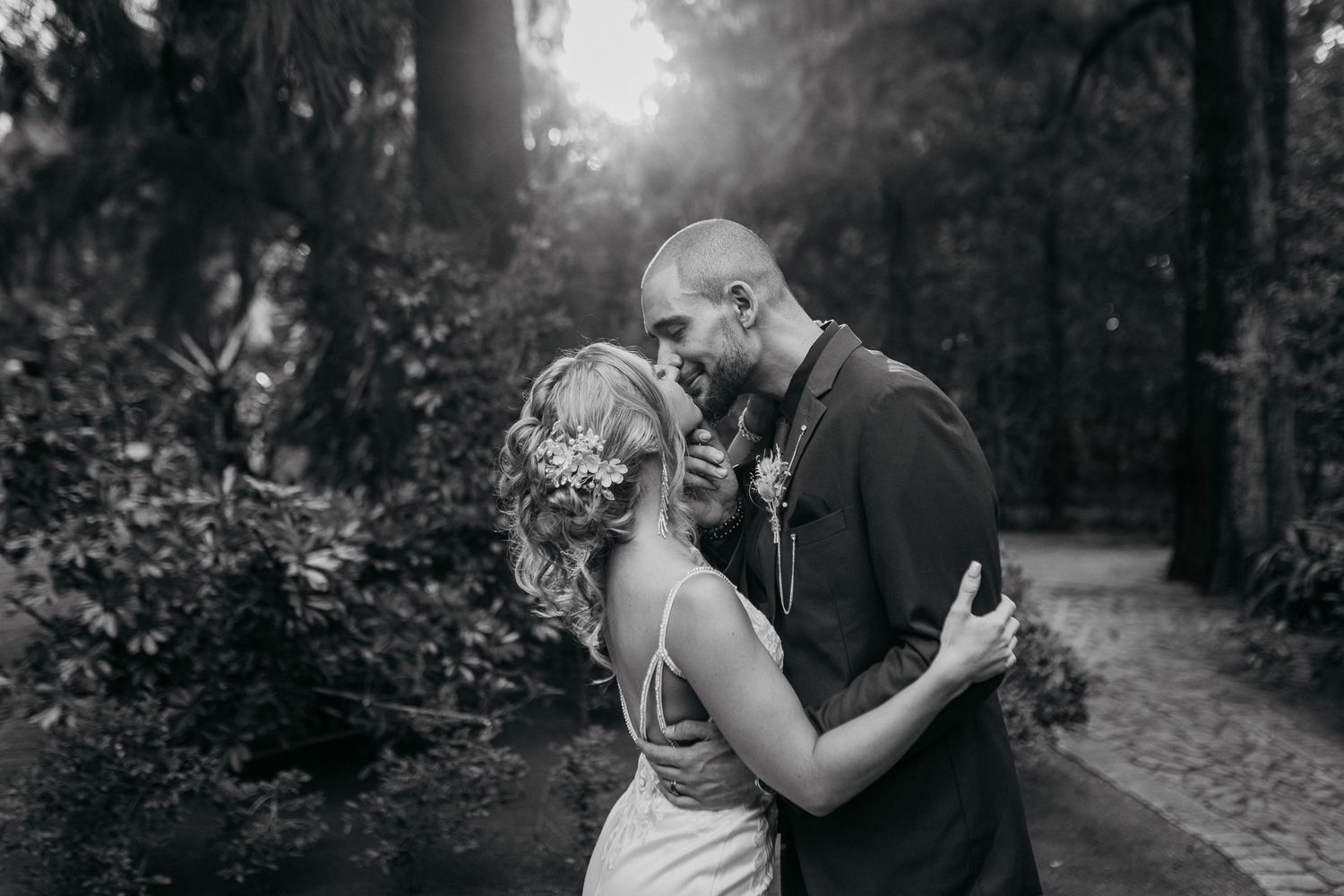 Romantic black and white portrait of couple embracing on wooded path.