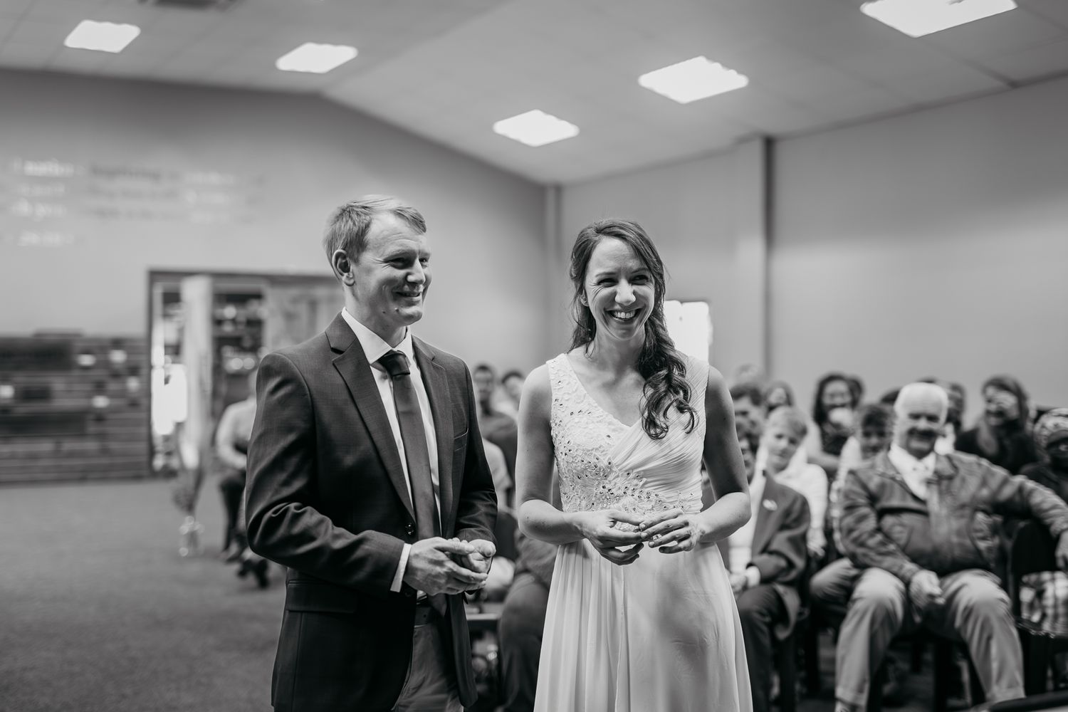 Black and white panorama of a wedding ceremony with guests seated in rows.