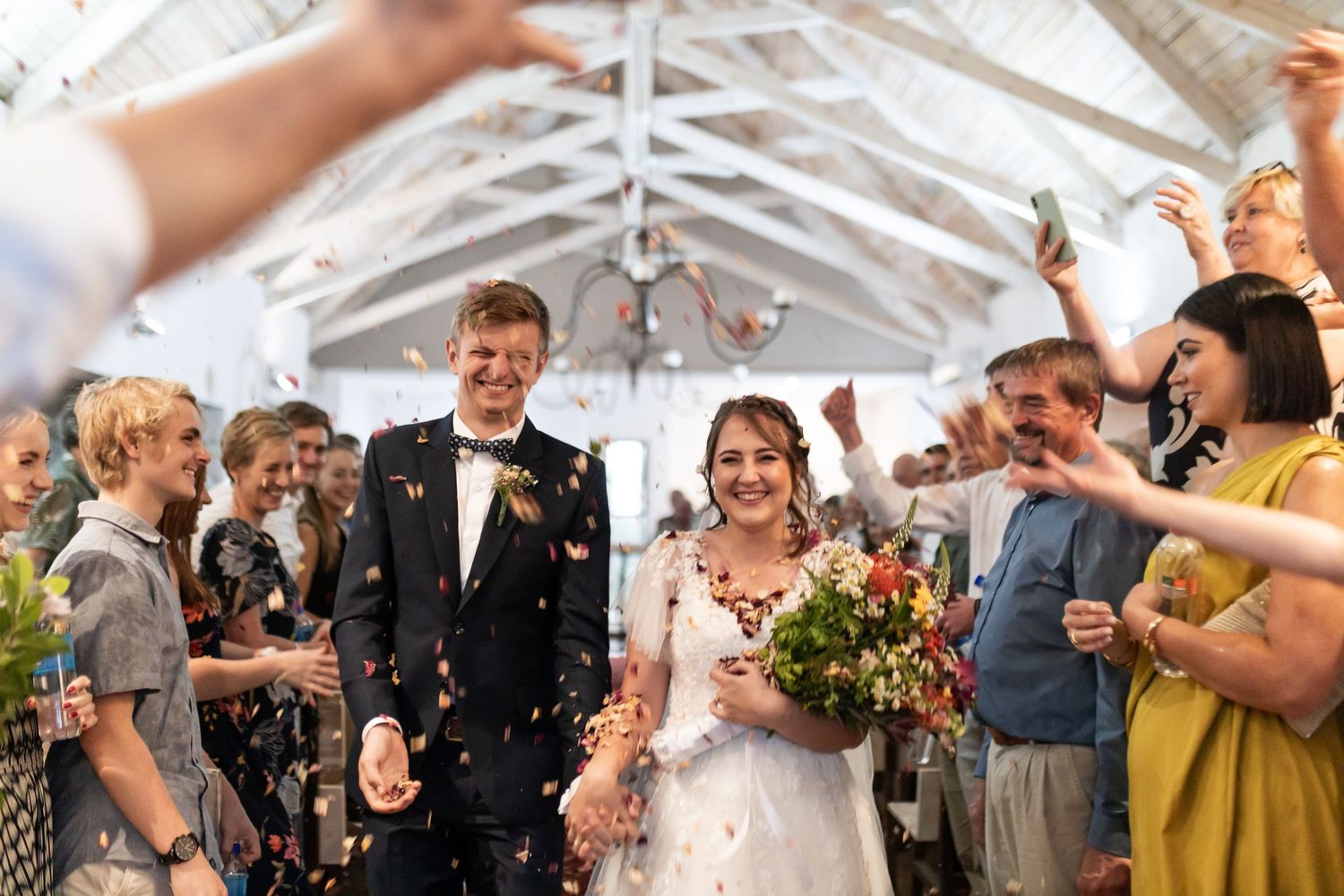 Joyful celebration with confetti at a wedding ceremony in a bright indoor venue.