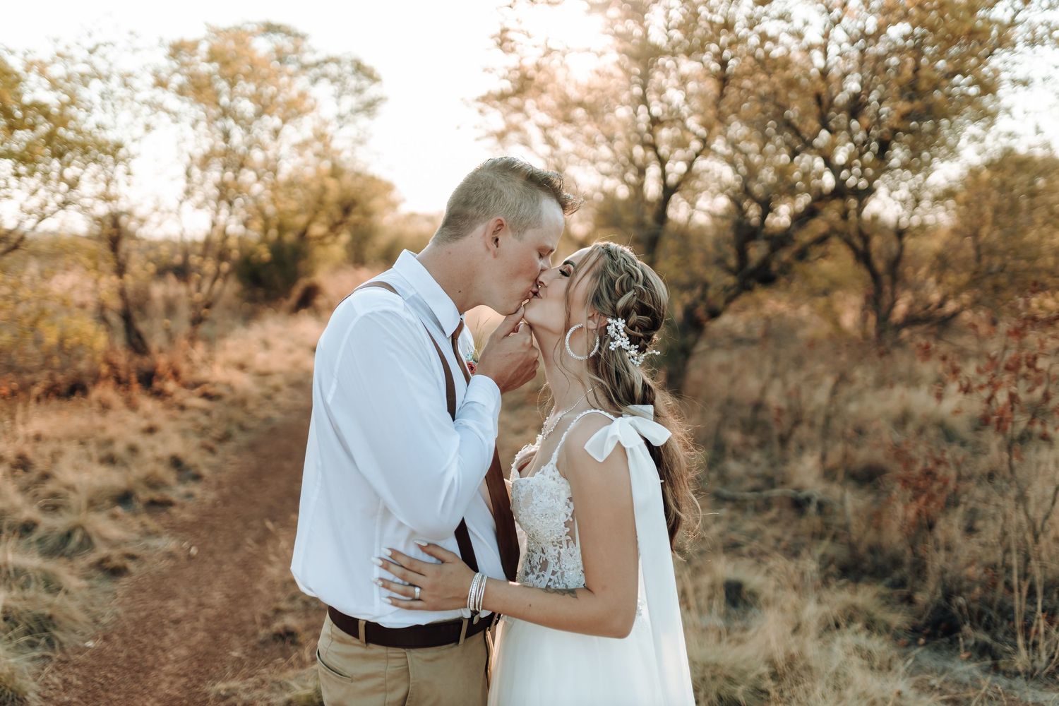 Newlyweds share a tender moment on a sunset-lit trail.