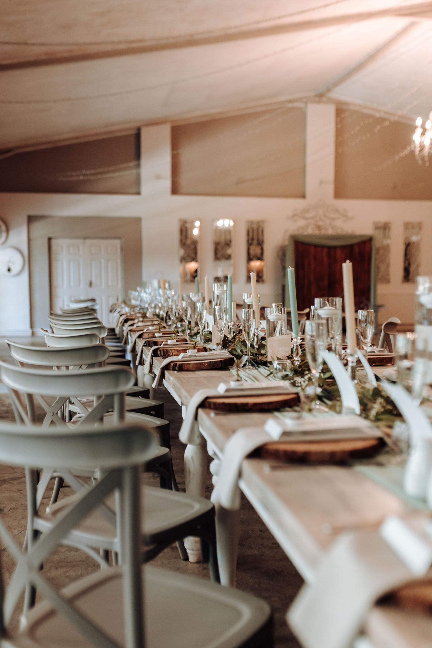 Long banquet table setup with grey chairs and rustic place settings in natural light.
